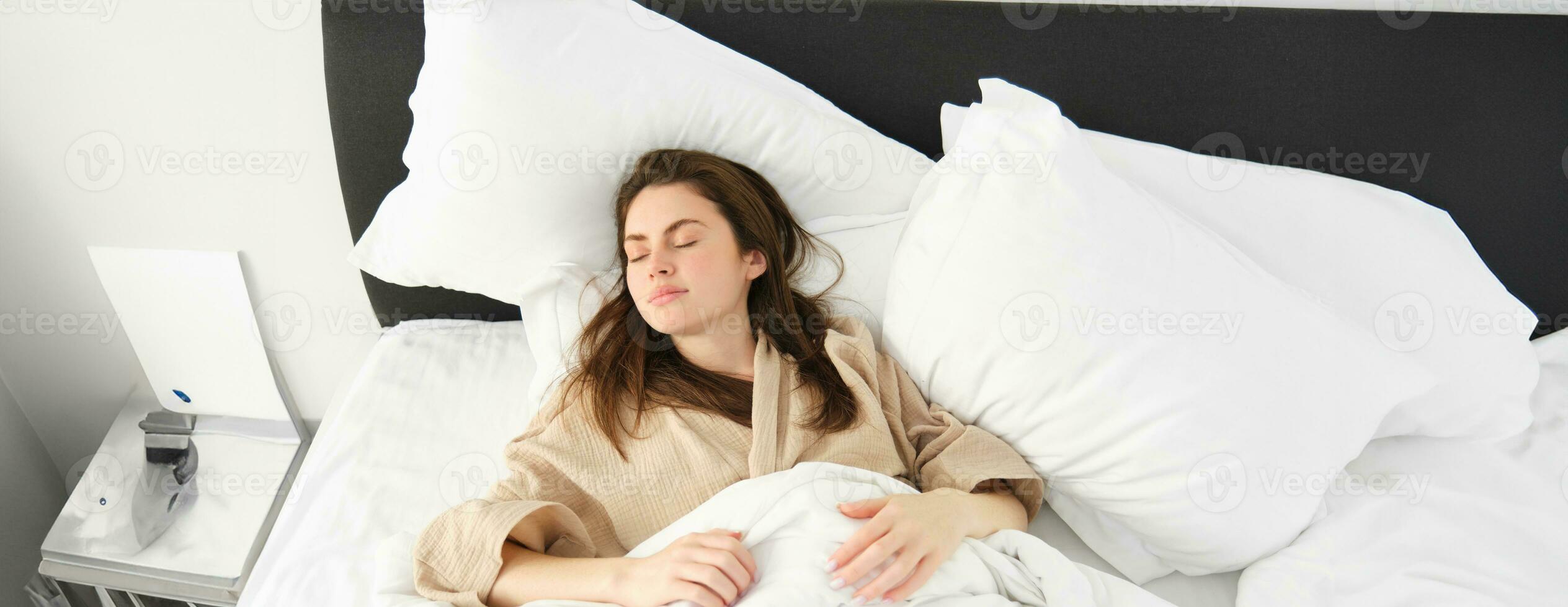 Haut vue de magnifique femme dans pyjamas dormant, repos dans lit avec fermé yeux, relaxant dans Hôtel pièce photo