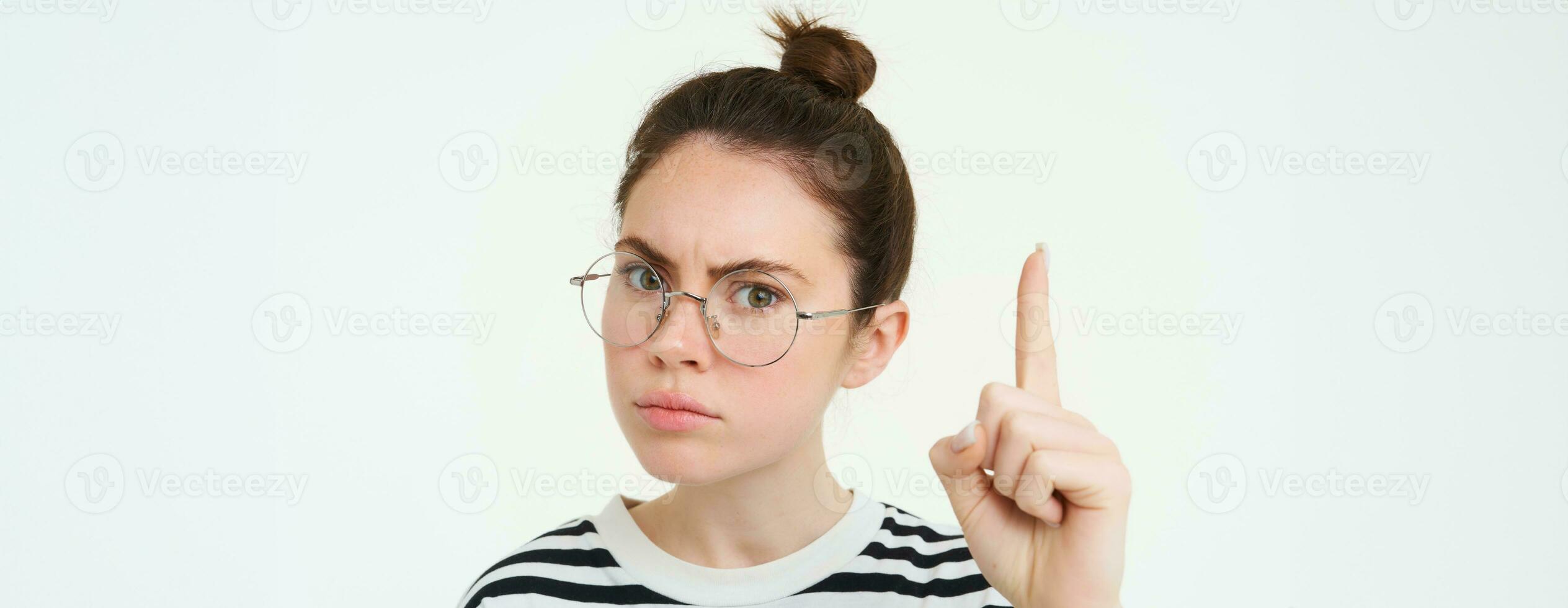 proche en haut portrait de sérieux femme dans lunettes, renfrogné et à la recherche concerné, montrer du doigt finge rup, montrant publicité sur haut, permanent plus de blanc Contexte photo