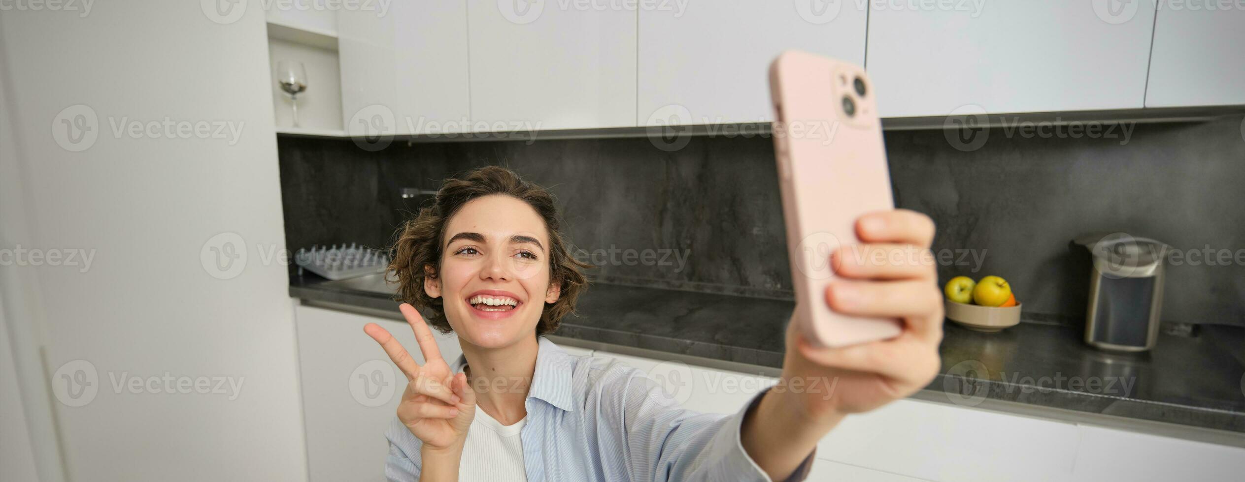content, magnifique brunette fille prend selfie à maison, pose pour photo avec téléphone intelligent