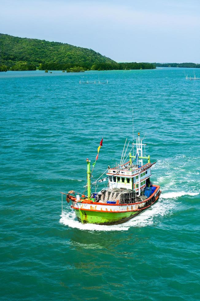 bateau de pêche flottant sur l'eau bleu mer et ciel photo