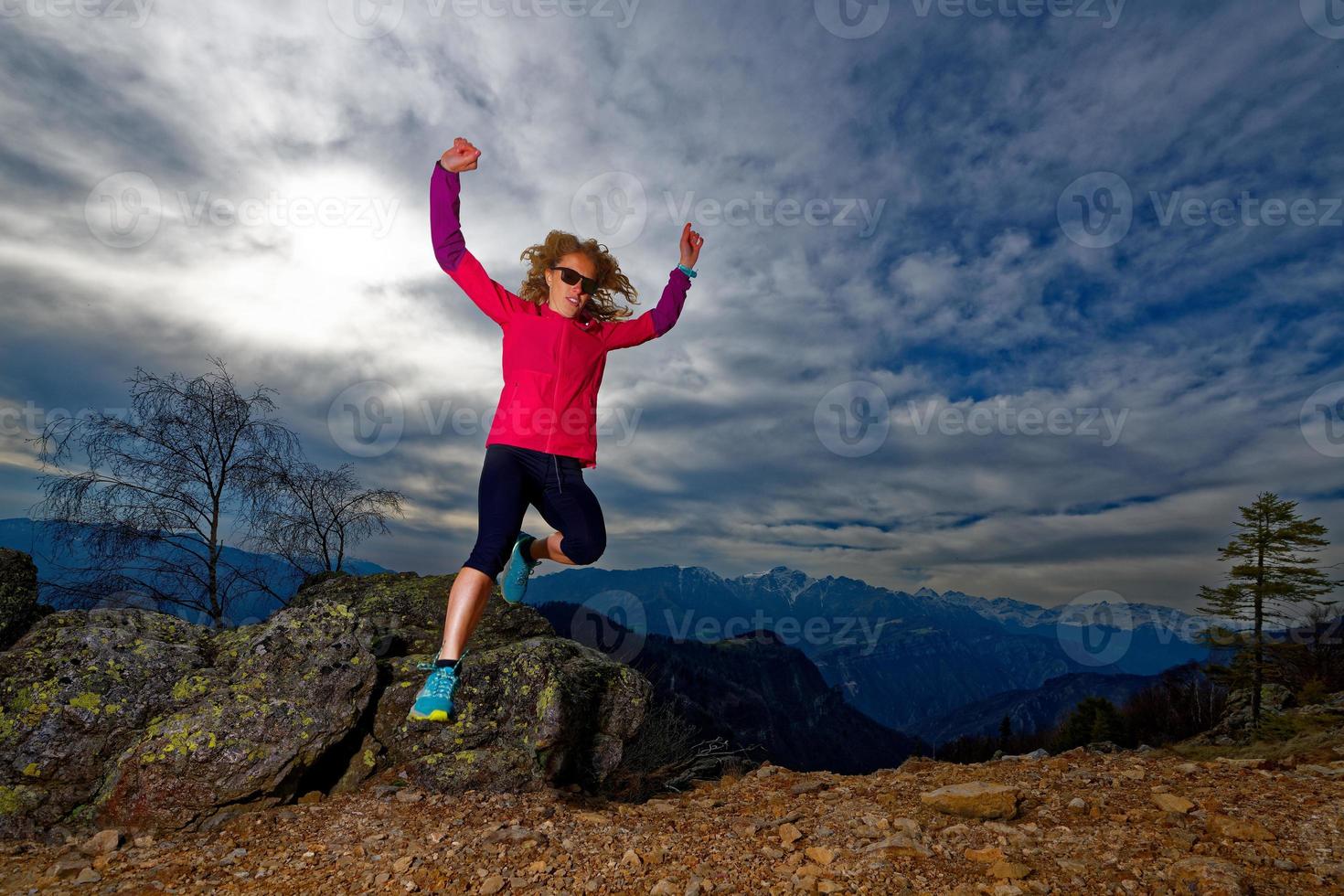 fille saute des rochers dans les montagnes lors d'une séance d'entraînement photo