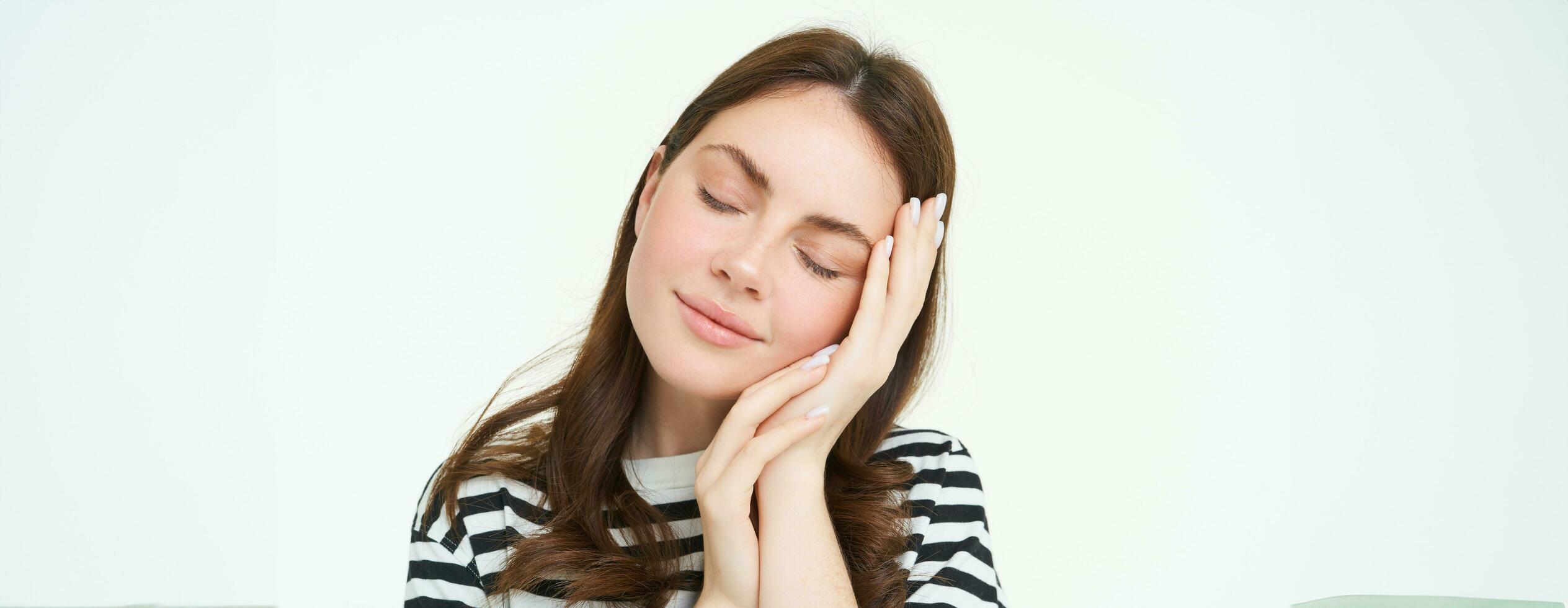 proche en haut portrait de offre, souriant Jeune femme, se ferme sa yeux et touche sa palmier, en train de dormir sur sa main, isolé sur blanc Contexte photo