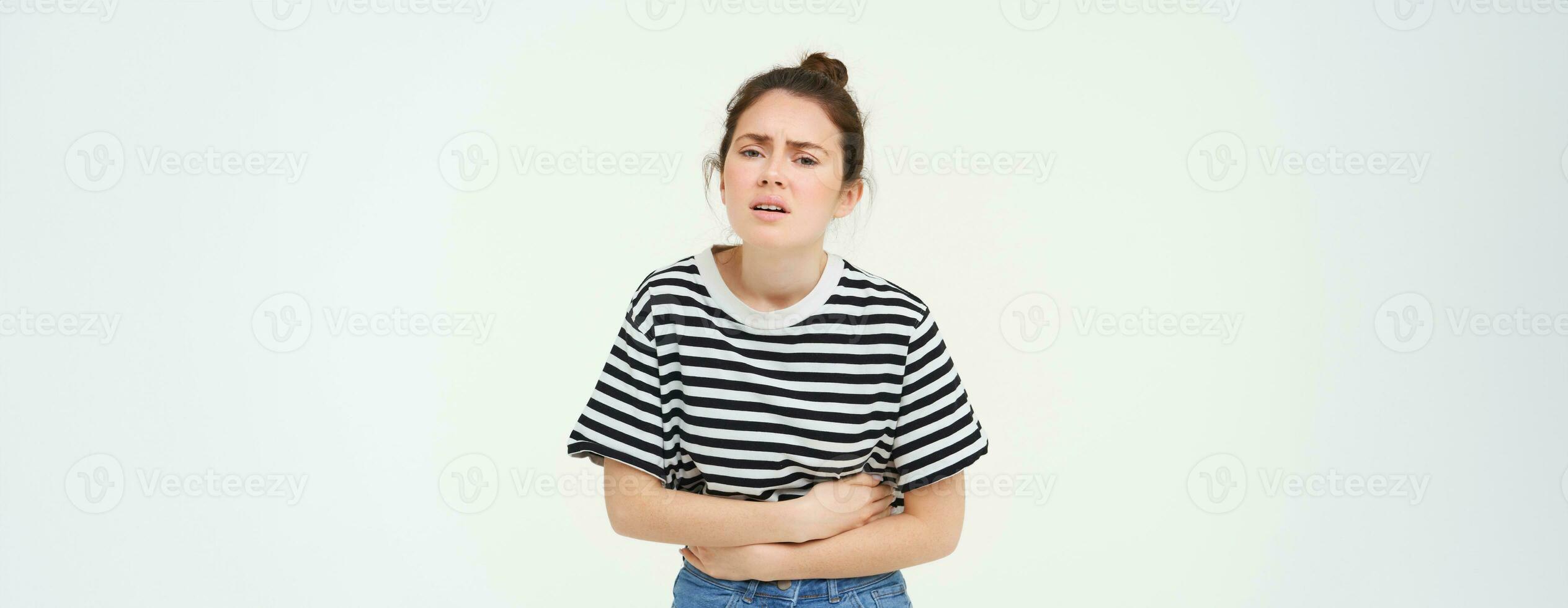 image de Jeune femme en portant mains sur sa ventre, sentiment inconfort, menstruel période crampes, Besoins analgésiques, des stands plus de blanc Contexte photo