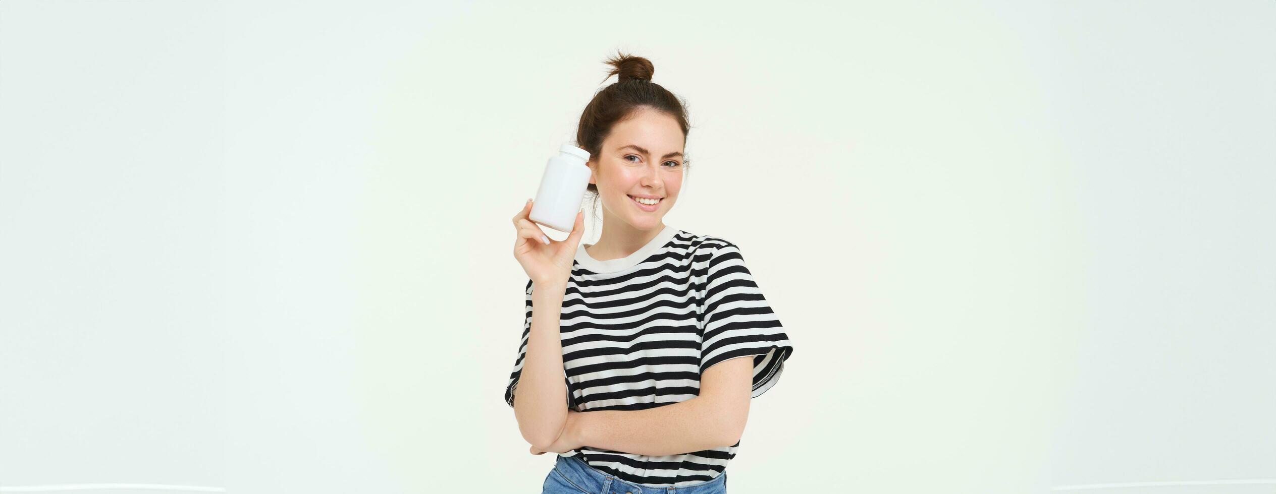 soins de santé et bien-être. Jeune femme en portant bouteille avec vitamines, diététique suppléments, traitement pour bien peau et cheveux, permanent plus de blanc Contexte photo