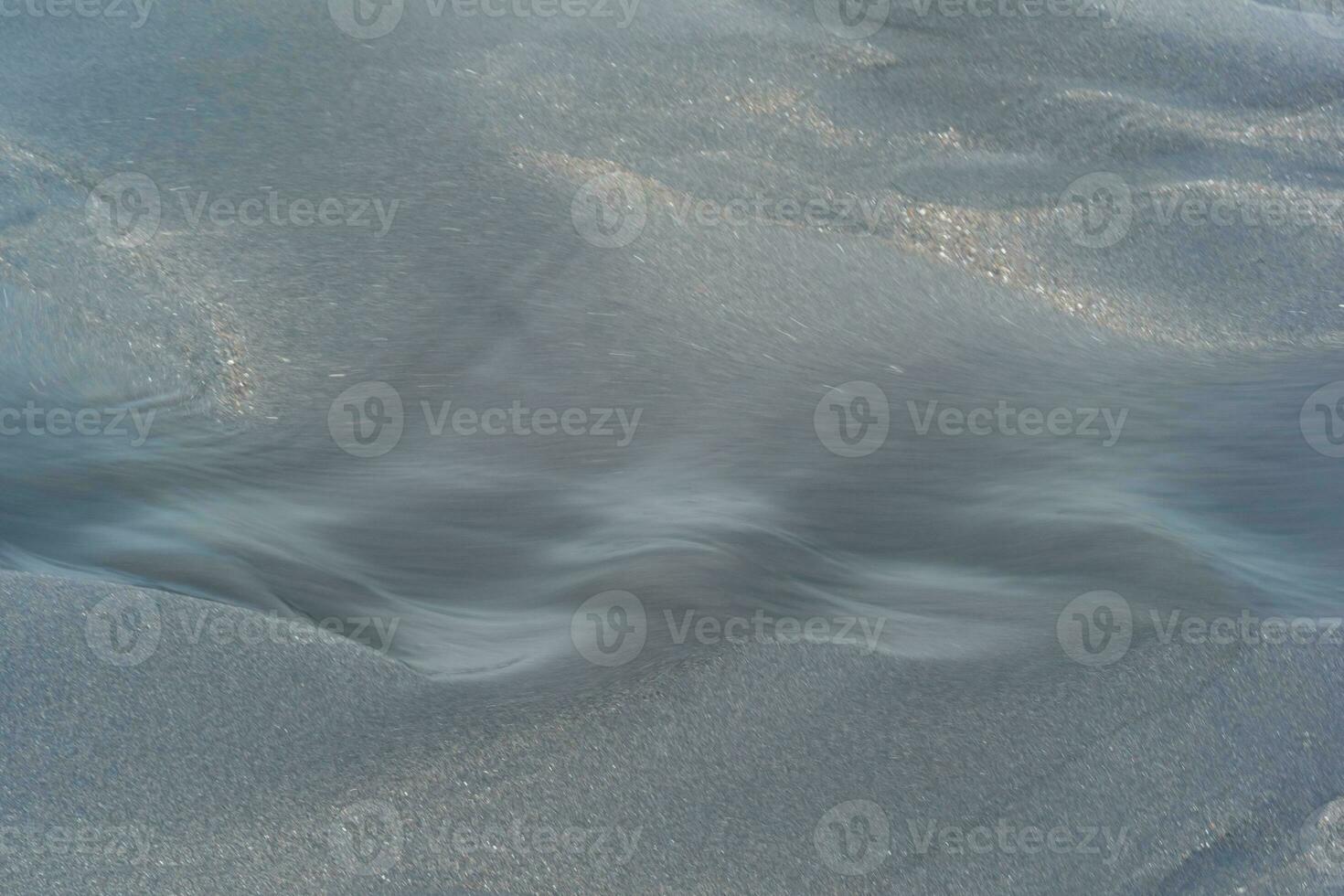 flou Naturel arrière-plan, l'eau les flux le long de le plage de noir volcanique le sable photo