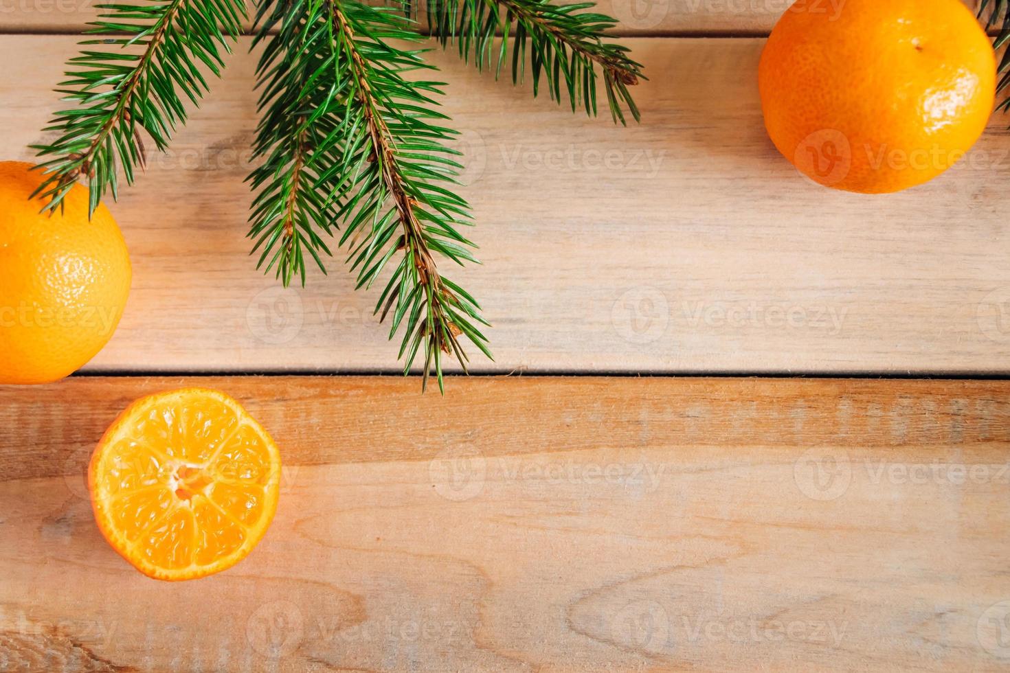 cadre fait de branches de sapin et de mandarines sur fond de bois. décor de noël. photo