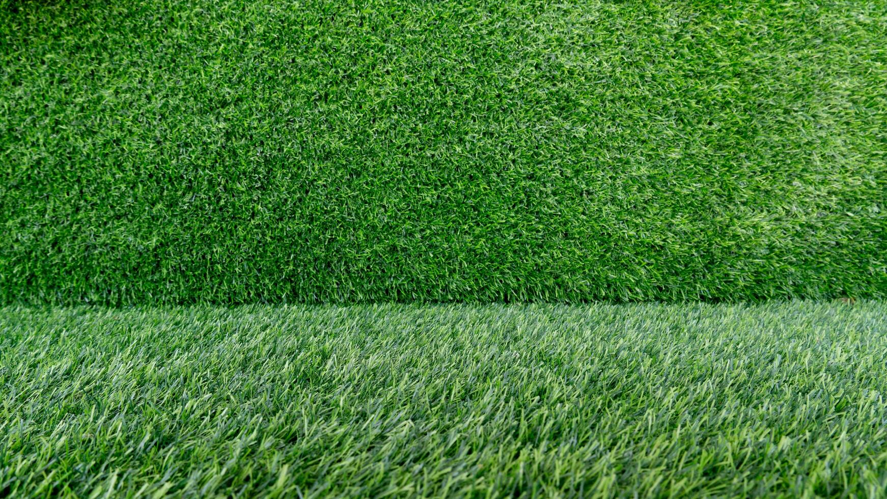 Contexte et surface de un artificiel vert herbe champ. adapté comme un illustration pour placement certain objets, tel comme brut matériaux. photo
