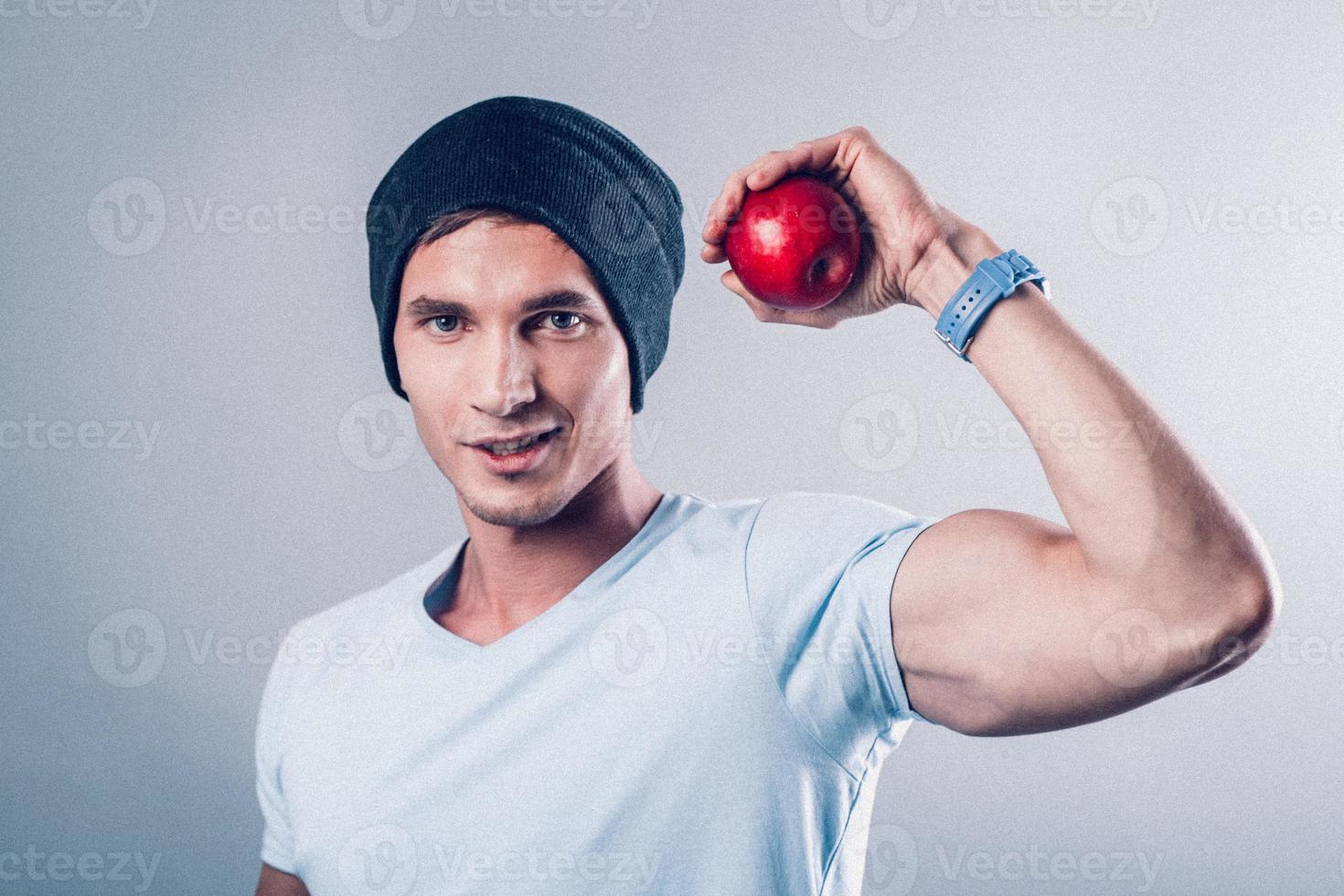 l'apparence sportive du jeune homme montre des muscles et tient des pommes dans ses mains photo