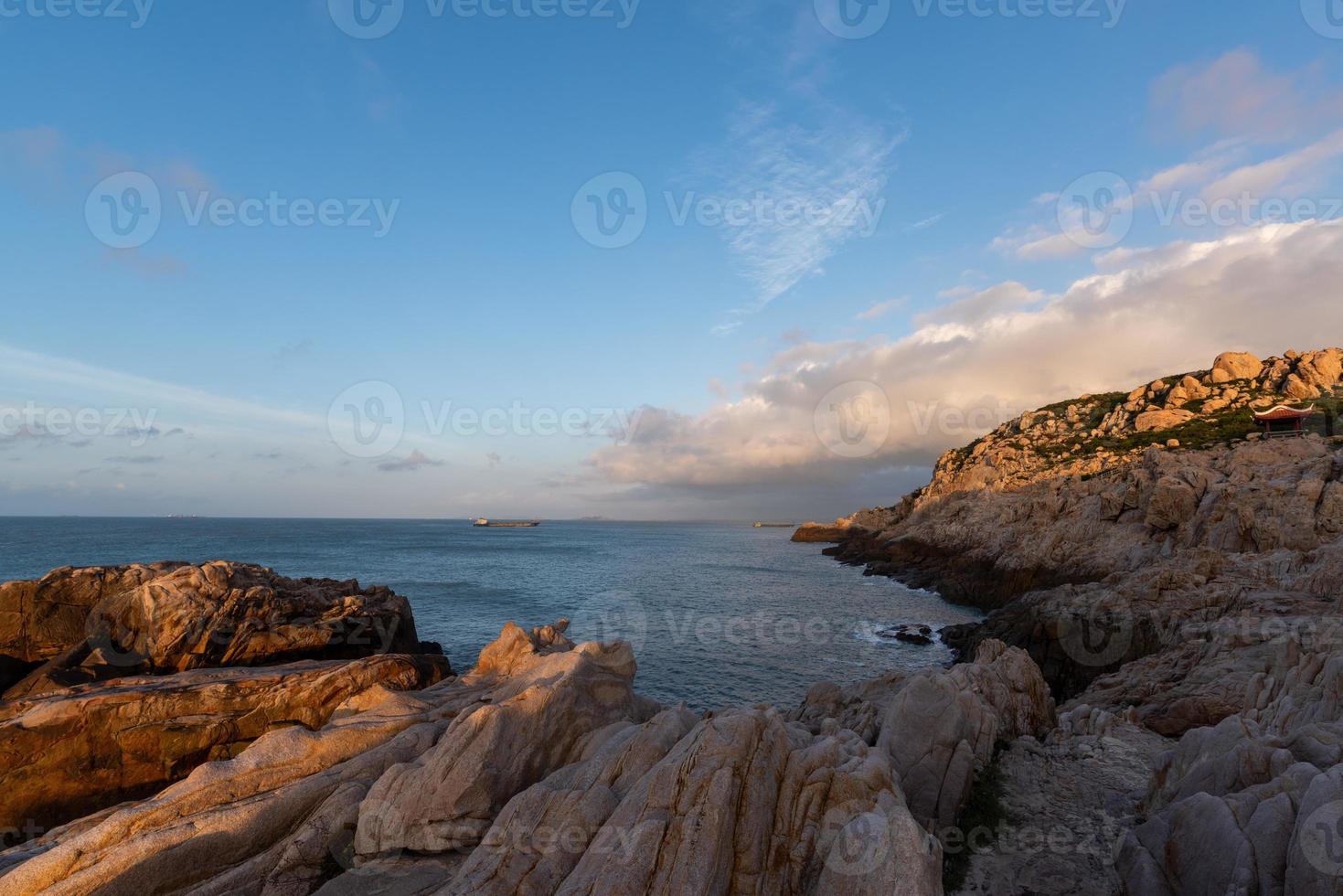 le matin, le soleil brille sur les rochers et les vagues sur la plage photo