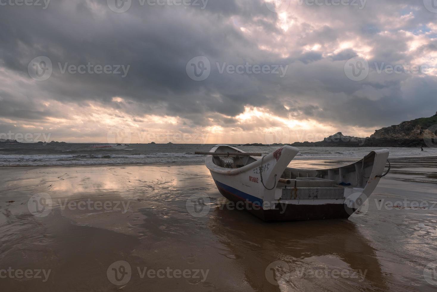 un petit bateau amarré sur la plage nuageuse, et le ciel était couvert de nuages sombres photo