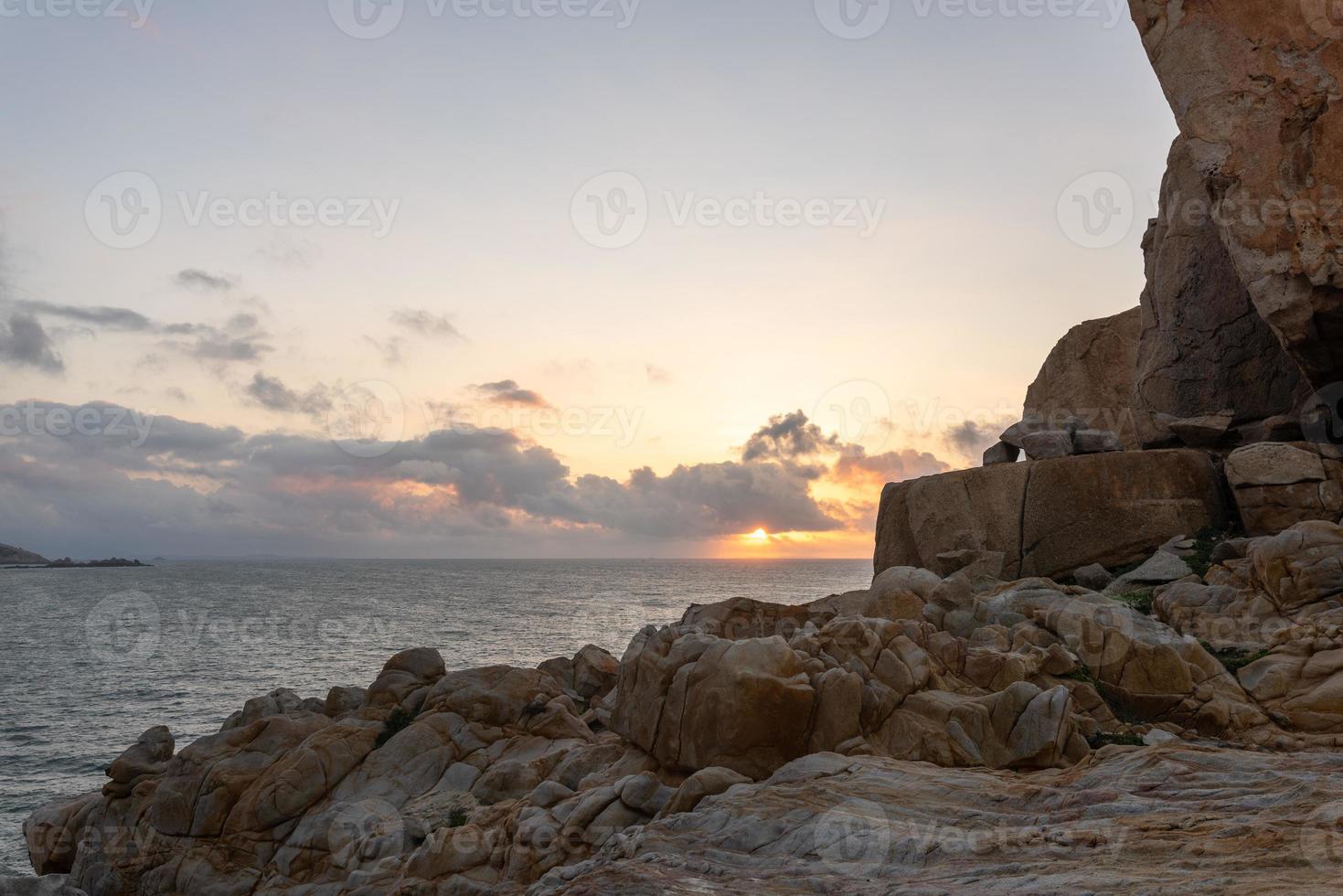 le matin, le soleil brille sur les rochers et les vagues sur la plage photo