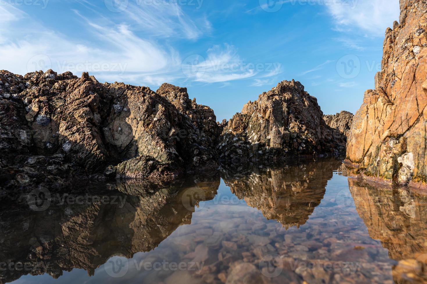 l'eau de mer entre les récifs balnéaires reflète les récifs jaunes et le ciel bleu photo