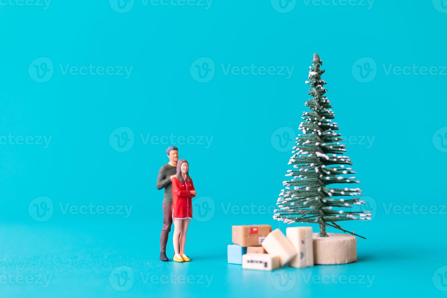 personnes miniatures, couple amoureux debout à côté d'un arbre de noël photo