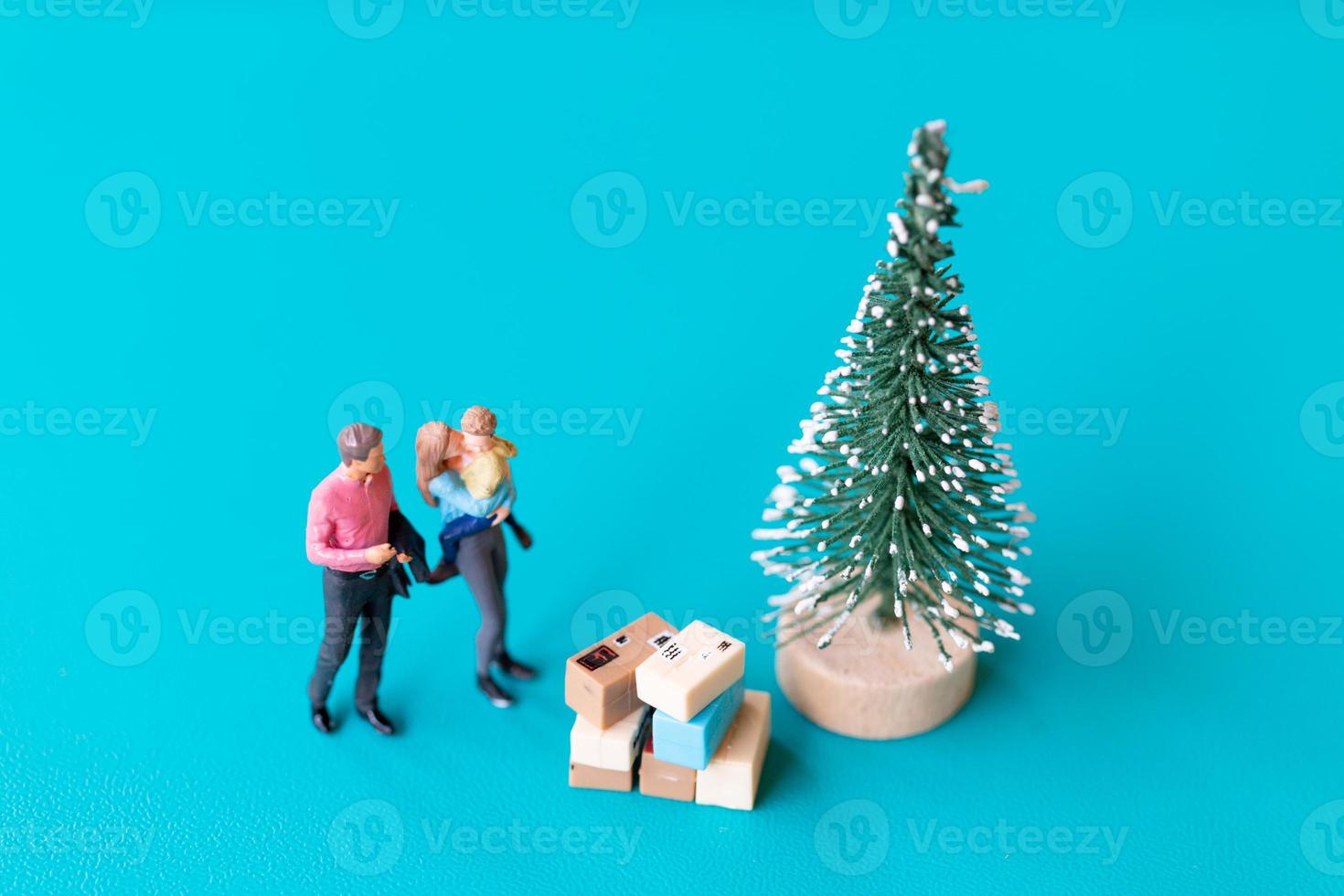 personnes miniatures, famille heureuse debout à côté d'un arbre de noël photo