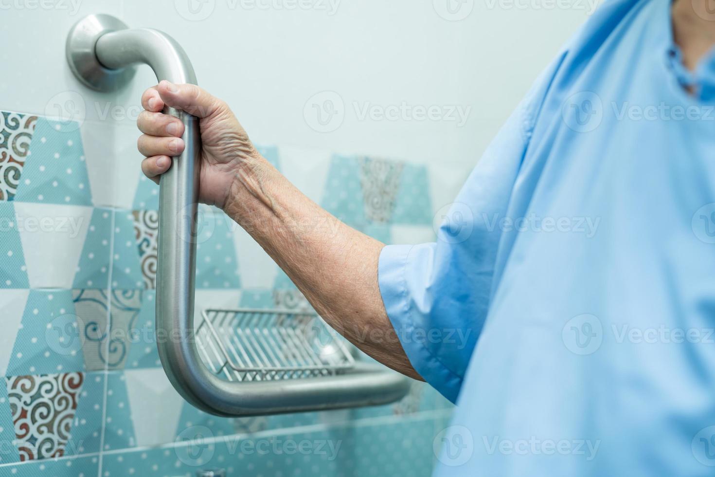 Une patiente asiatique âgée utilise la sécurité de la poignée avec l'aide de l'assistant de soutien dans l'hôpital de soins infirmiers concept médical solide et sain. photo