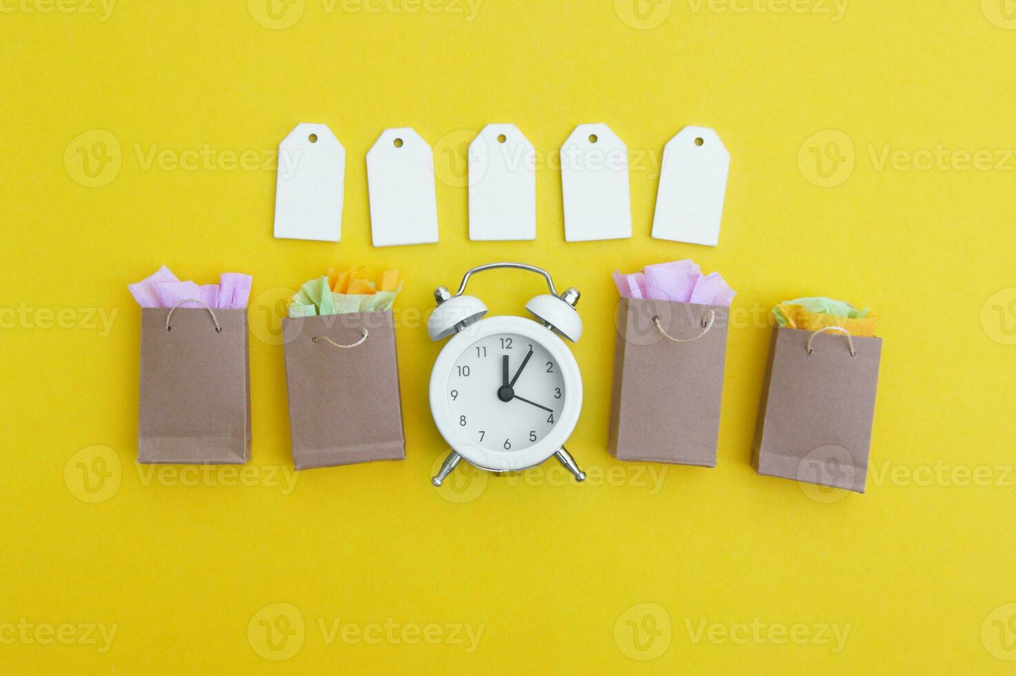 Vide Étiquettes avec papier Sacs, un ancien blanc l'horloge sur une brillant Jaune Contexte. photo