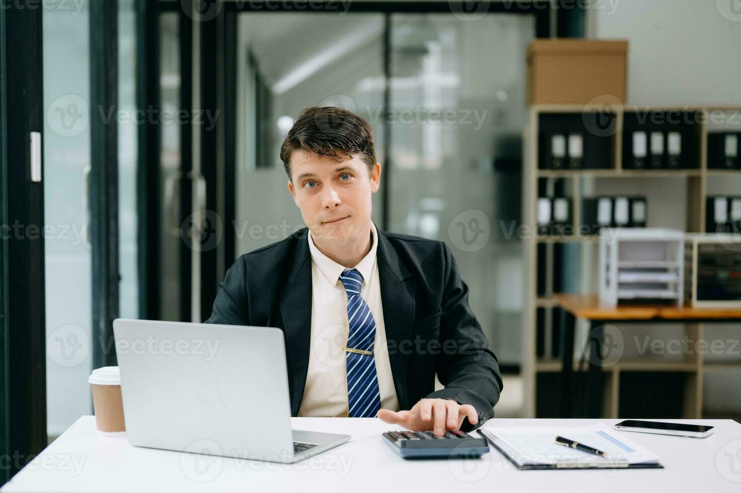 Jeune homme d'affaire travail à Bureau avec ordinateur portable, tablette et prise Remarques sur le papier. photo