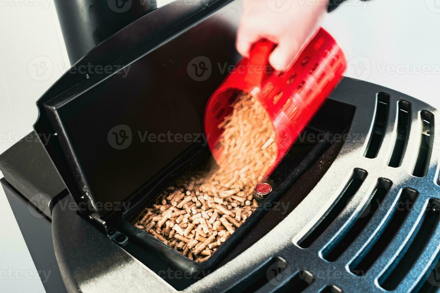 fermer sur pellets, noir national pastille poêle, homme chargement par main granules avec une rouge 3 ré imprimé tasse photo