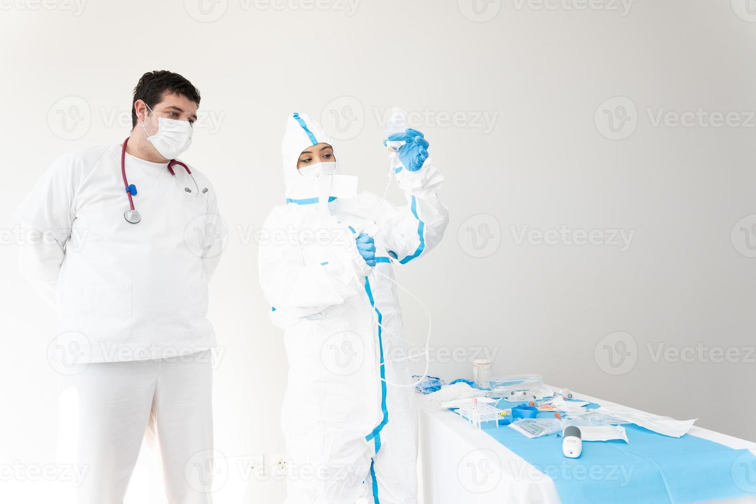 médecin en masque et costume de protection à l'aide d'un compte-gouttes à l'hôpital photo