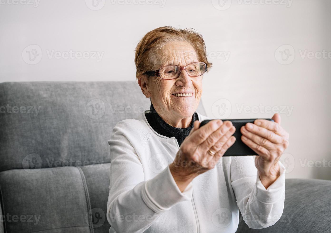 femme âgée souriante ayant un appel vidéo sur smartphone photo