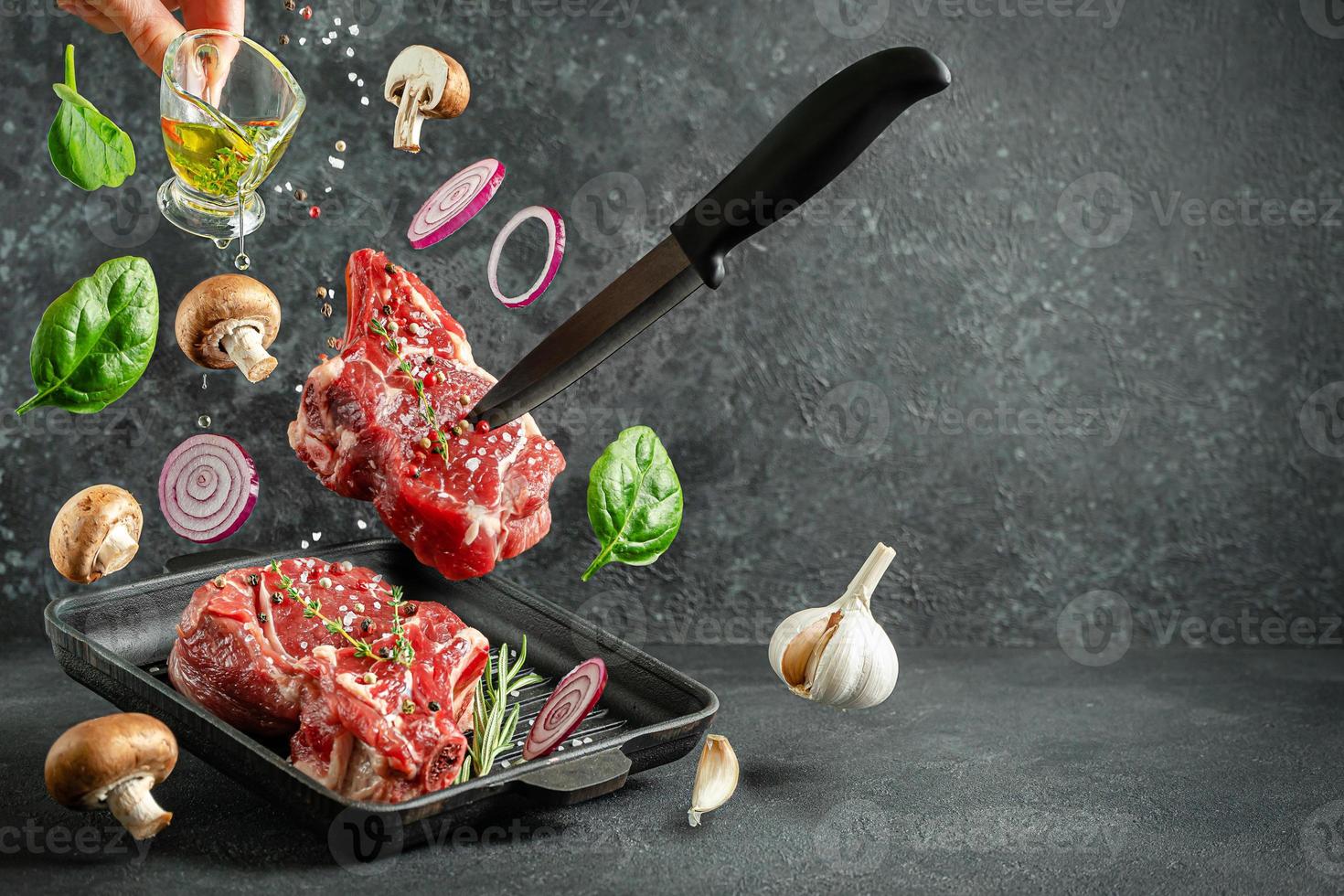 steak d'os de veau cru tombant sur la lèchefrite avec des ingrédients pour la cuisson sur fond sombre. espace de copie. photo