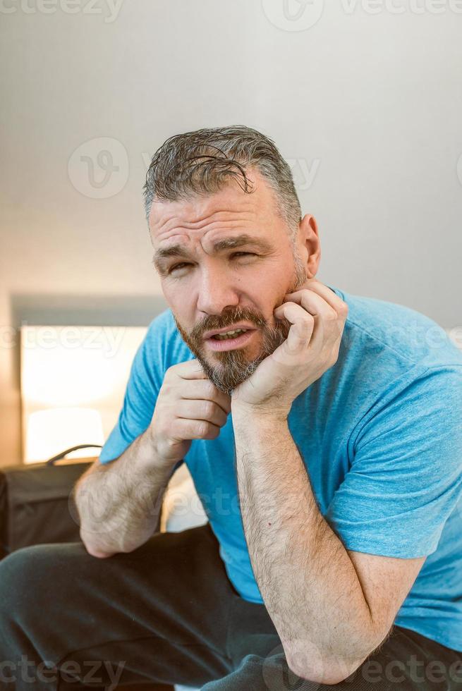 malheureux bel homme assis seul sur le lit dans la chambre. divorce, insomnie, dépression, troubles photo