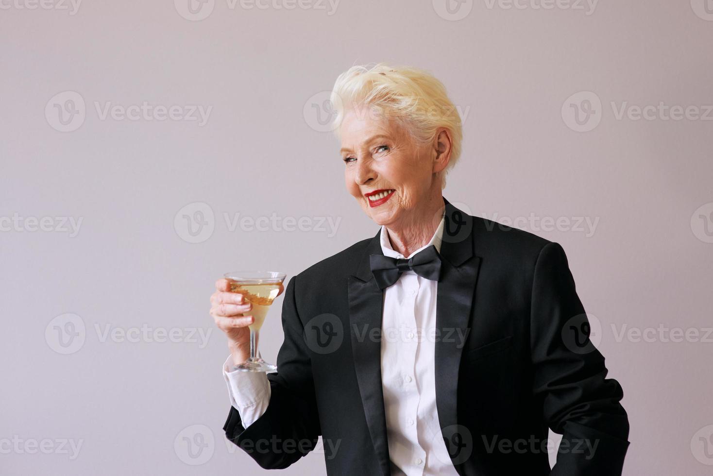 élégante femme senior sommelier mature en smoking avec verre de vin mousseux. amusement, fête, style, style de vie, alcool, concept de célébration photo