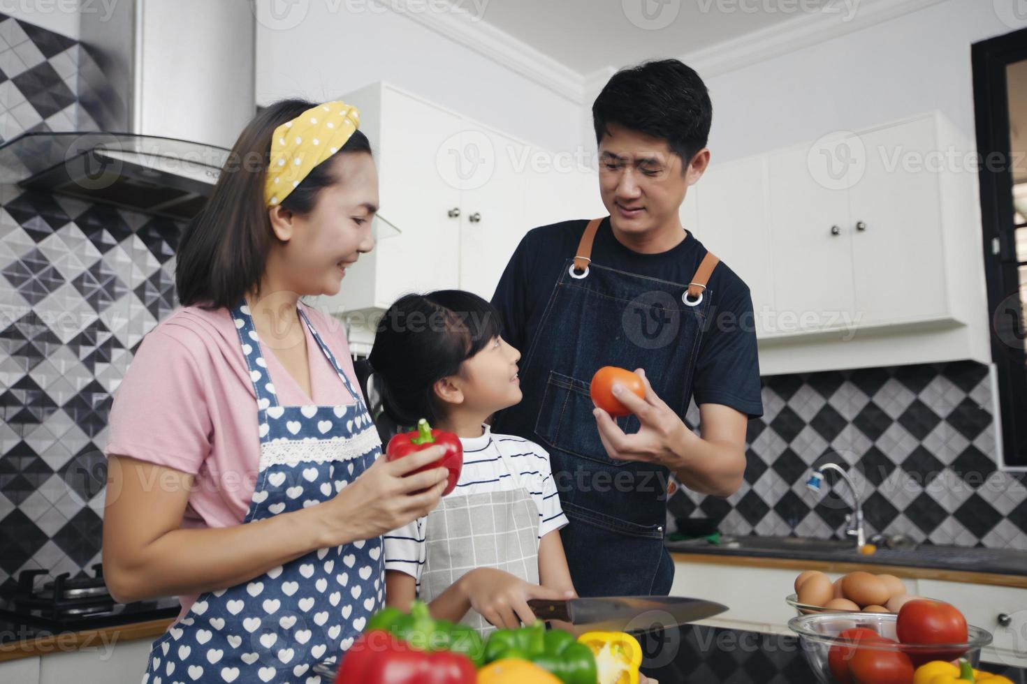 une famille heureuse a papa, maman et leur petite fille qui cuisinent ensemble dans la cuisine photo