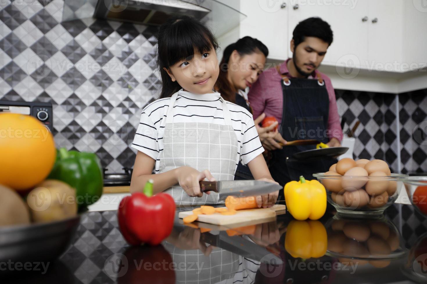 une famille heureuse a papa, maman et leur petite fille qui cuisinent ensemble dans la cuisine photo