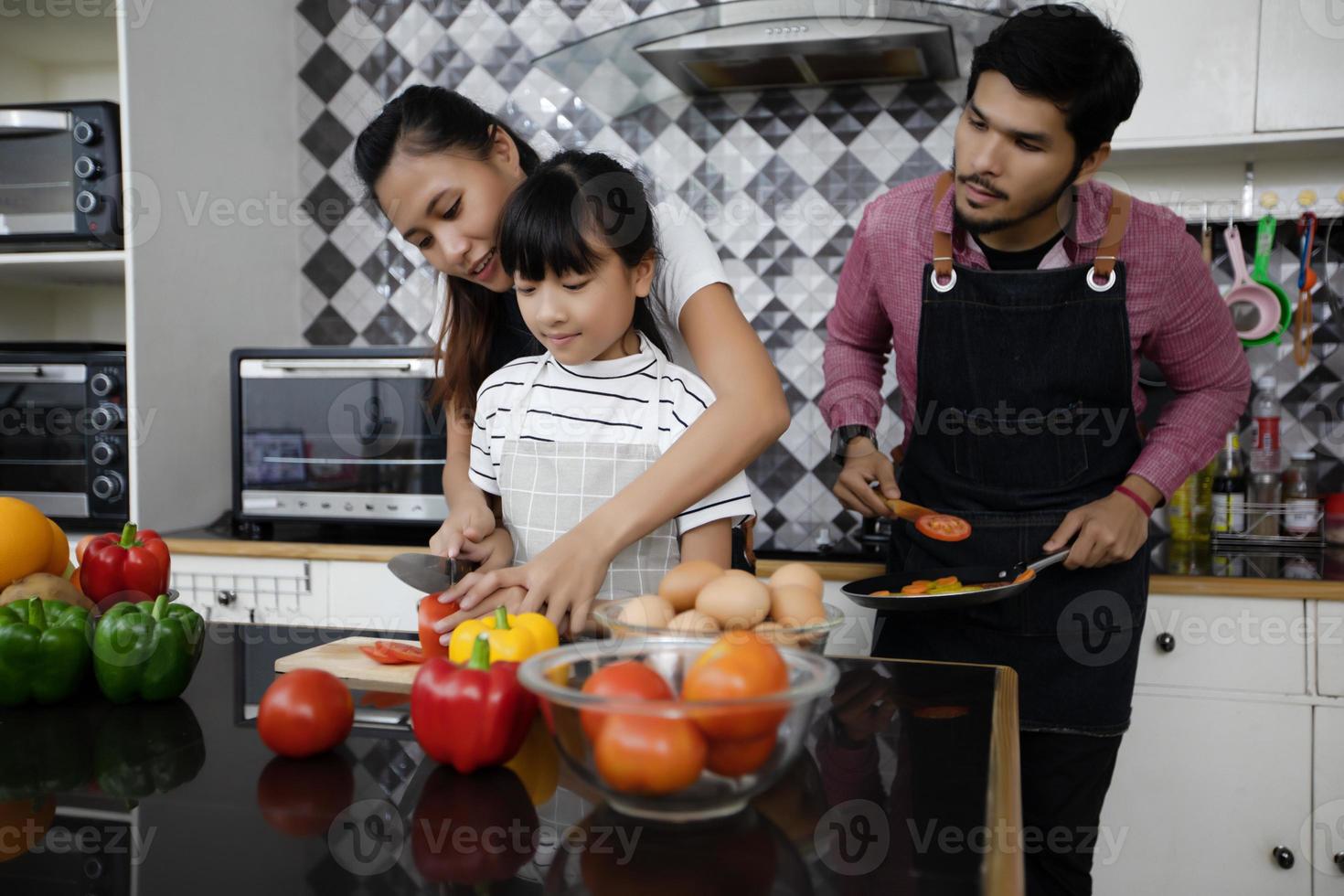 une famille heureuse a papa, maman et leur petite fille qui cuisinent ensemble dans la cuisine photo