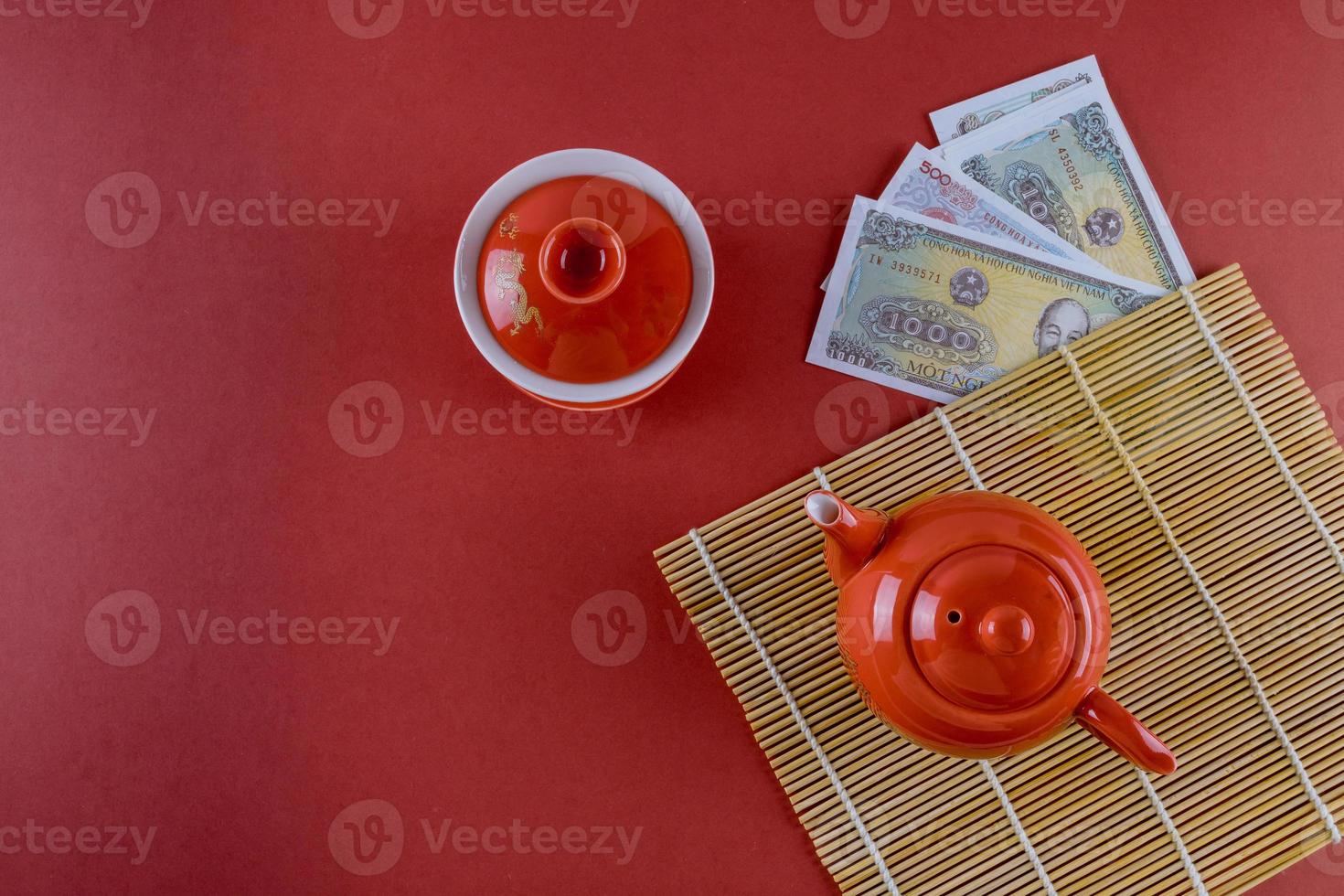 célébrer les décorations du festival asiatique le nouvel an vietnamien cérémonie festive thé avec de l'argent dong vietnamien sur fond rouge photo