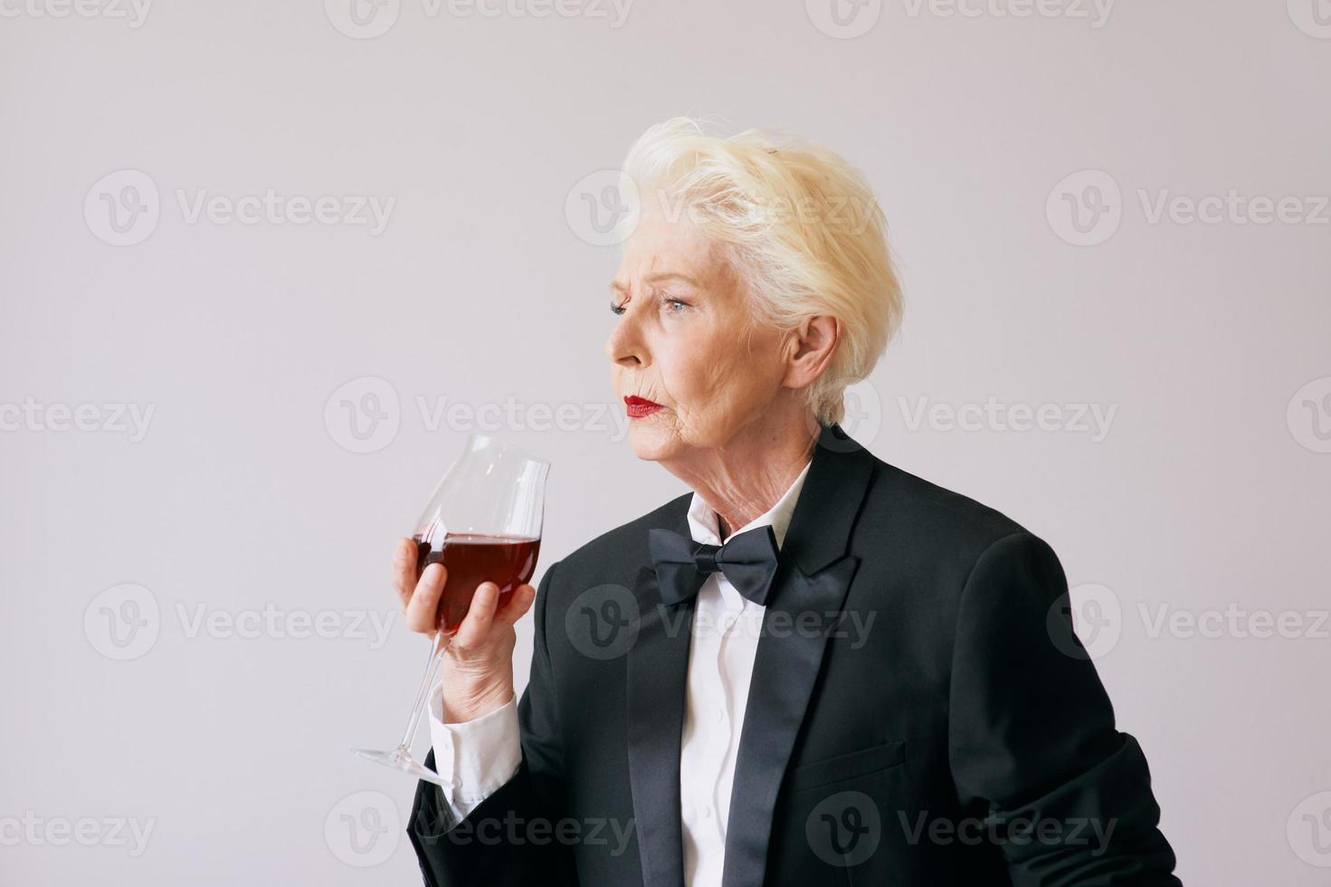 femme sommelière senior élégante en smoking avec verre ou vin rouge. boisson, mature, concept de style photo