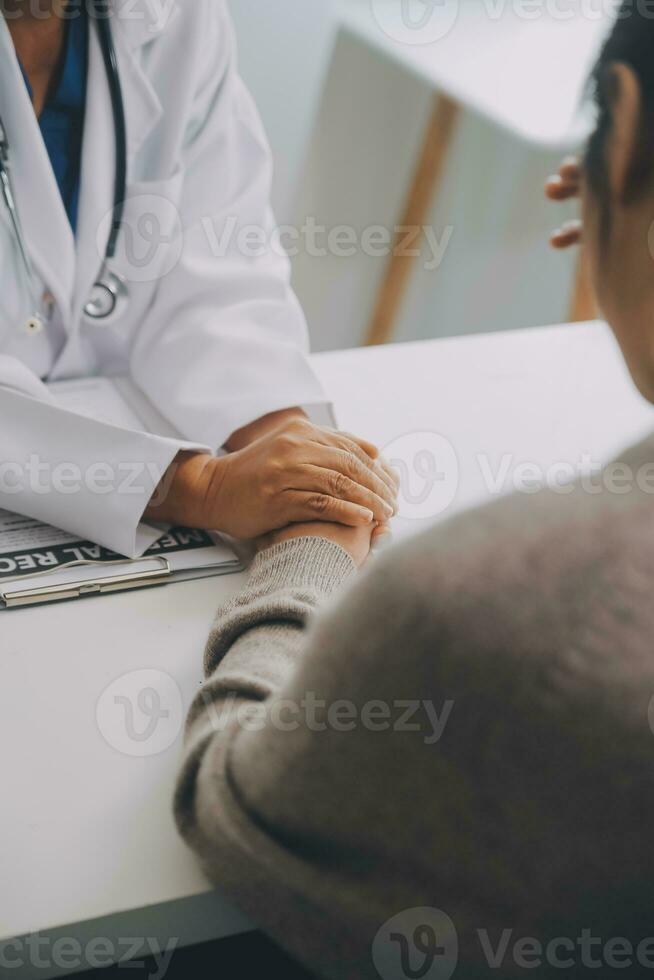 médecin et patient séance près chaque autre à le table dans clinique bureau. le concentrer est sur femelle médecin mains rassurant femme, seulement mains, proche en haut. médicament concept photo