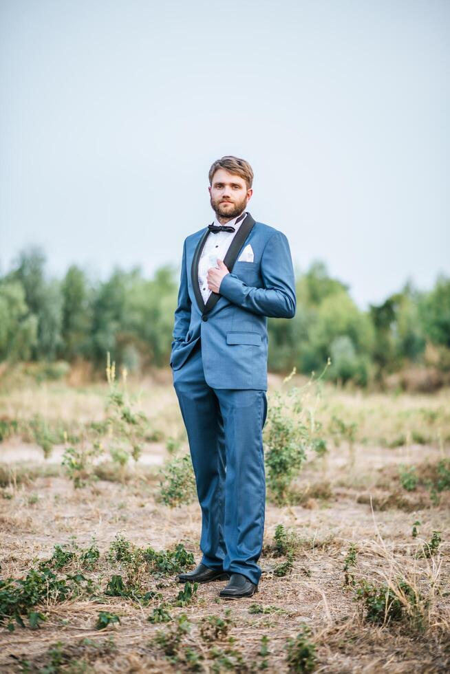 beau marié en costume de mariage affichage dans le parc photo