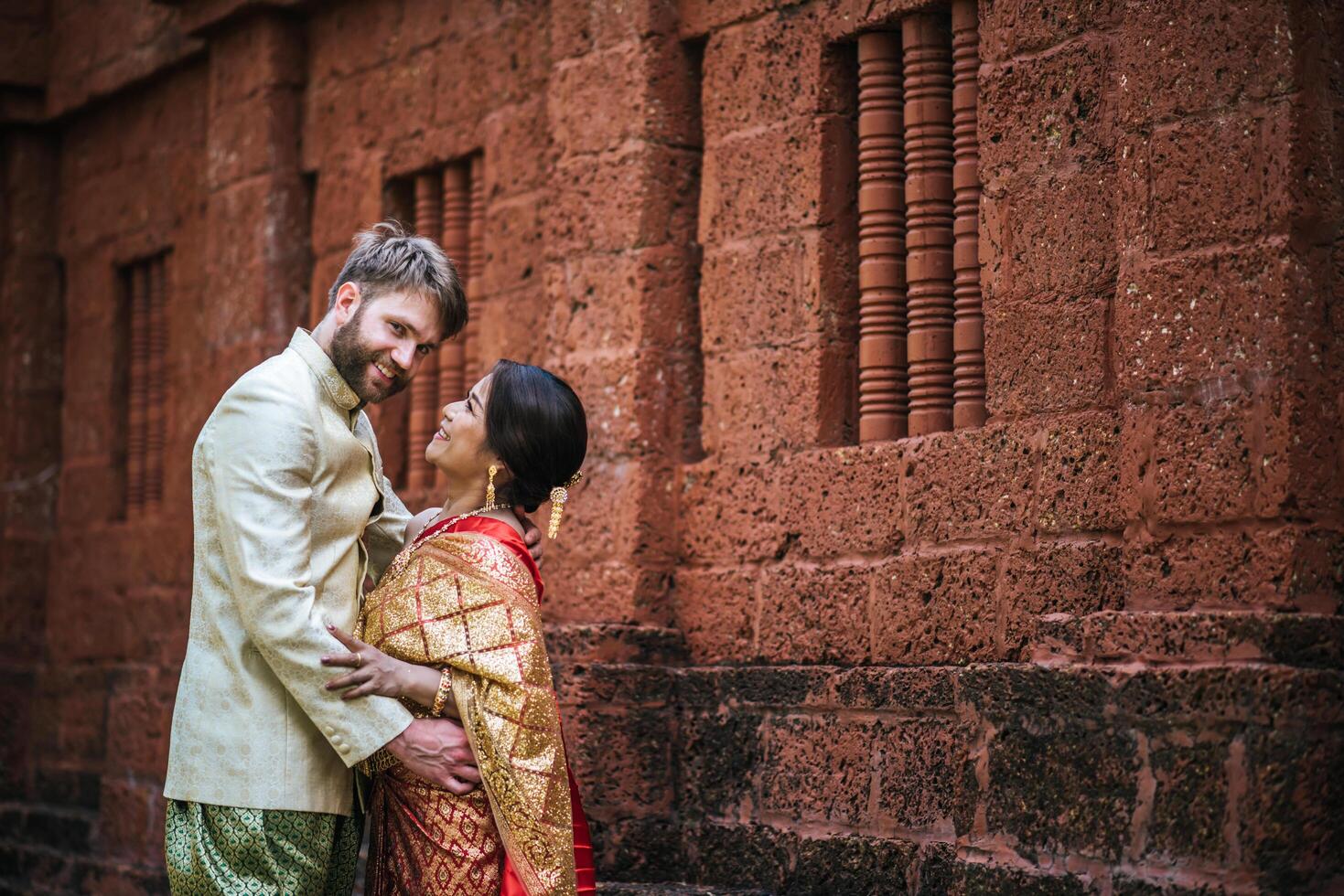 la mariée asiatique et le marié caucasien passent un moment romantique avec une robe thaïlandaise photo