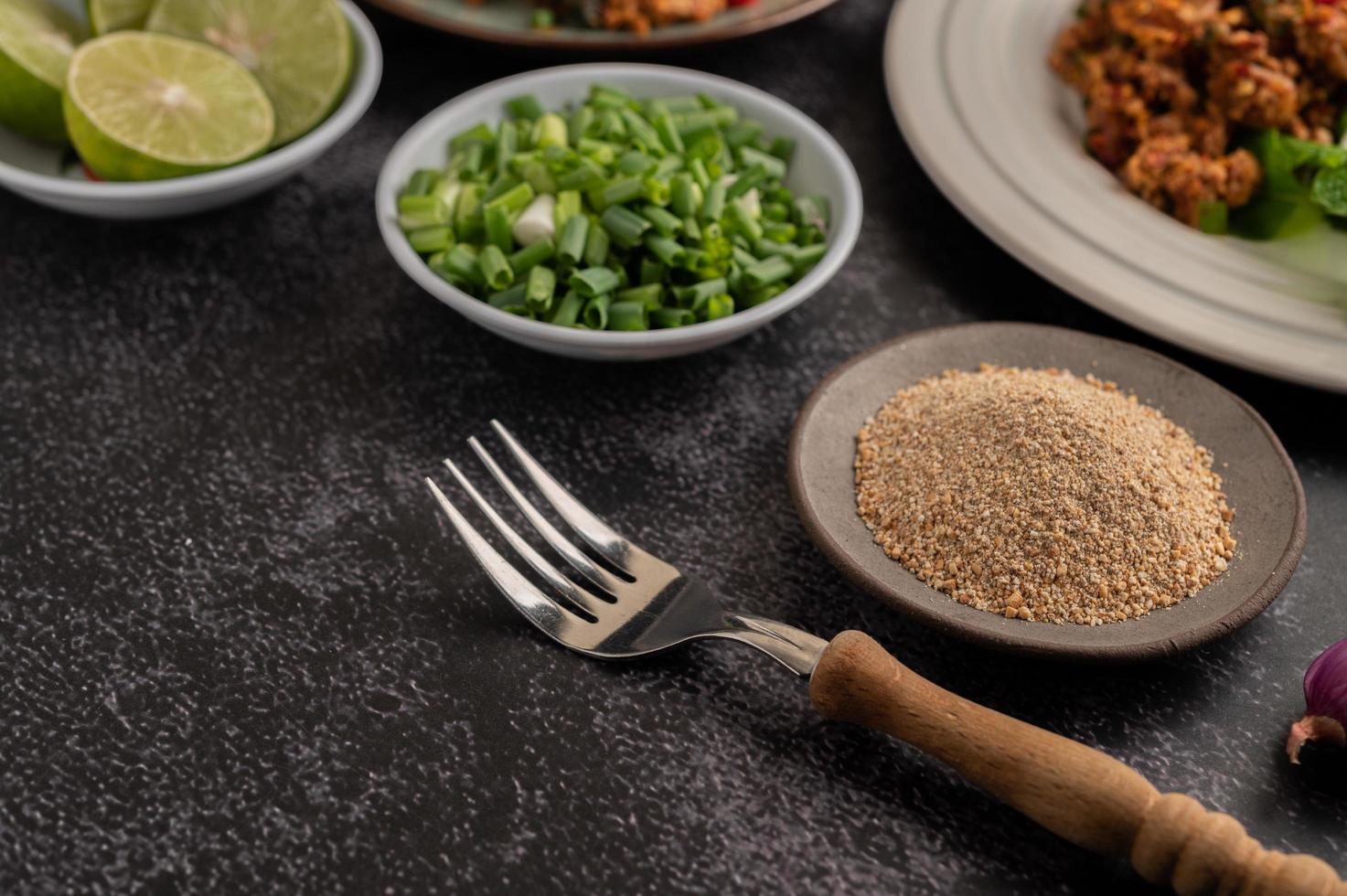 fourchette, riz rôti, oignons verts hachés et citron vert coupé en deux sur un sol en ciment noir. photo