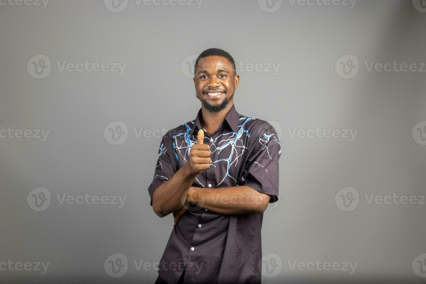 souriant homme posant avec bras franchi sur blanc Contexte et fait les pouces en haut photo