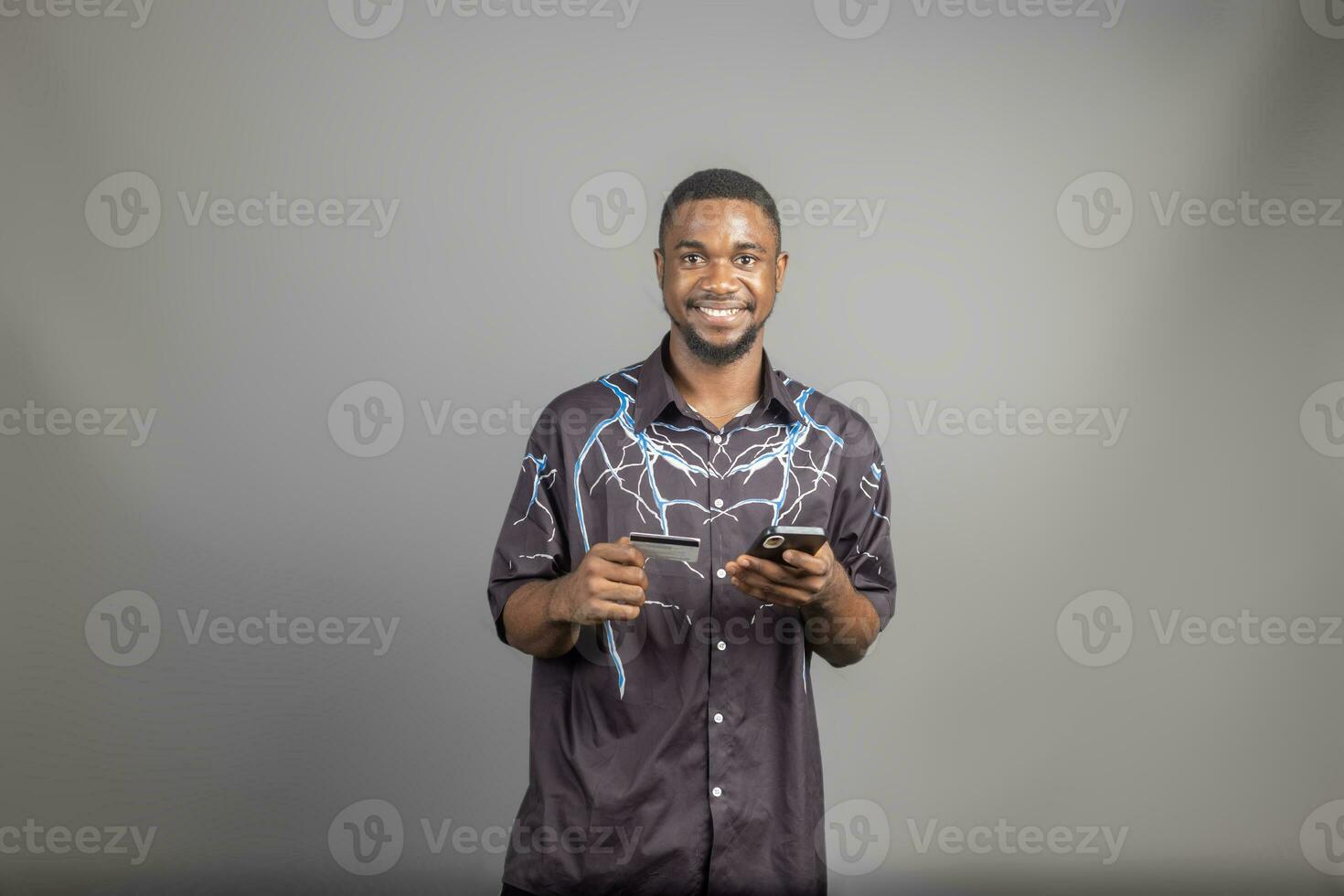 Beau Jeune noir homme en utilisant le sien crédit carte et téléphone à magasin en ligne, bancaire en ligne concepts photo