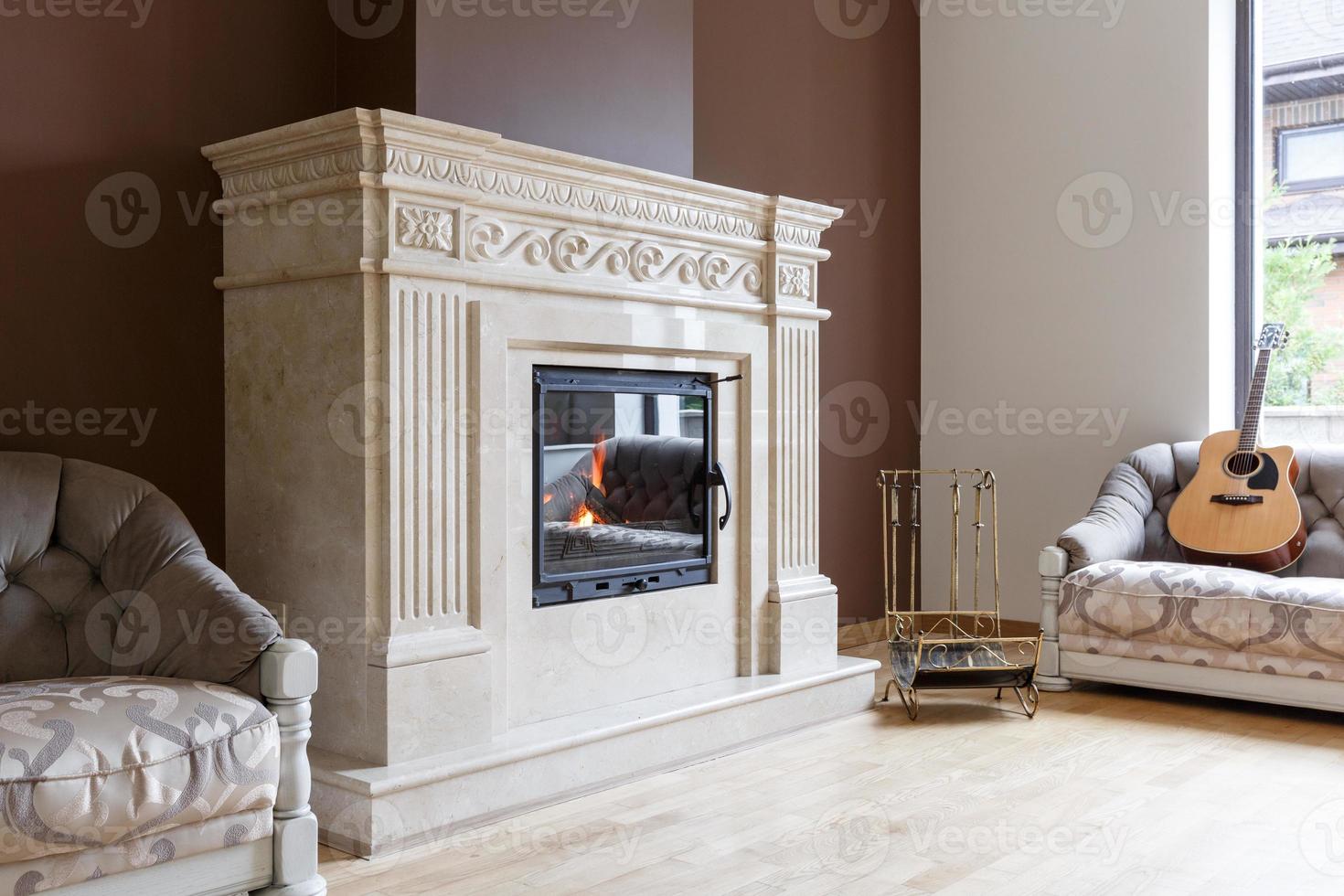 cheminée en marbre blanc de style classique avec du bois brûlant à l'intérieur. photo