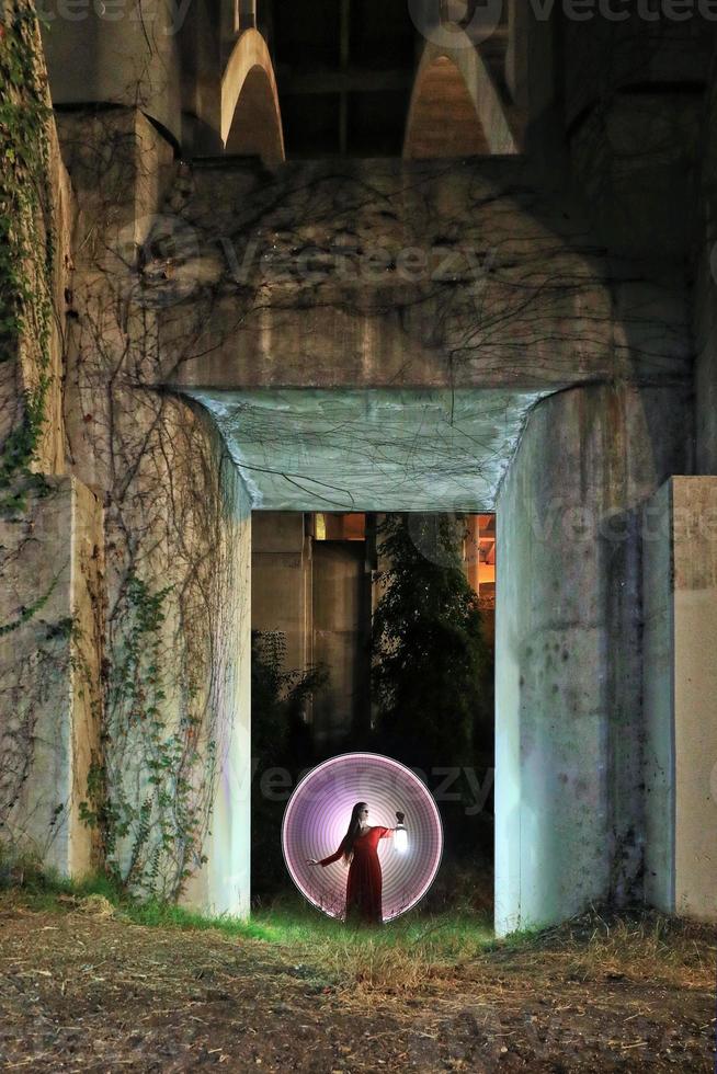 fille tenant une lanterne dans une porte en béton avec des vignes photo