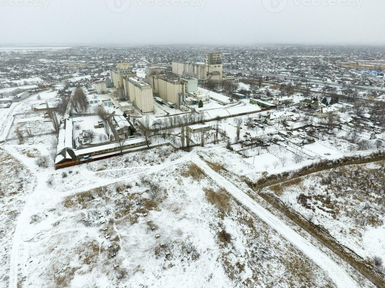 saupoudré avec neige grain ascenseur. hiver vue de le vieux soviétique ascenseur. hiver vue de le des oiseaux œil vue de le village. le des rues sont couvert avec neige photo