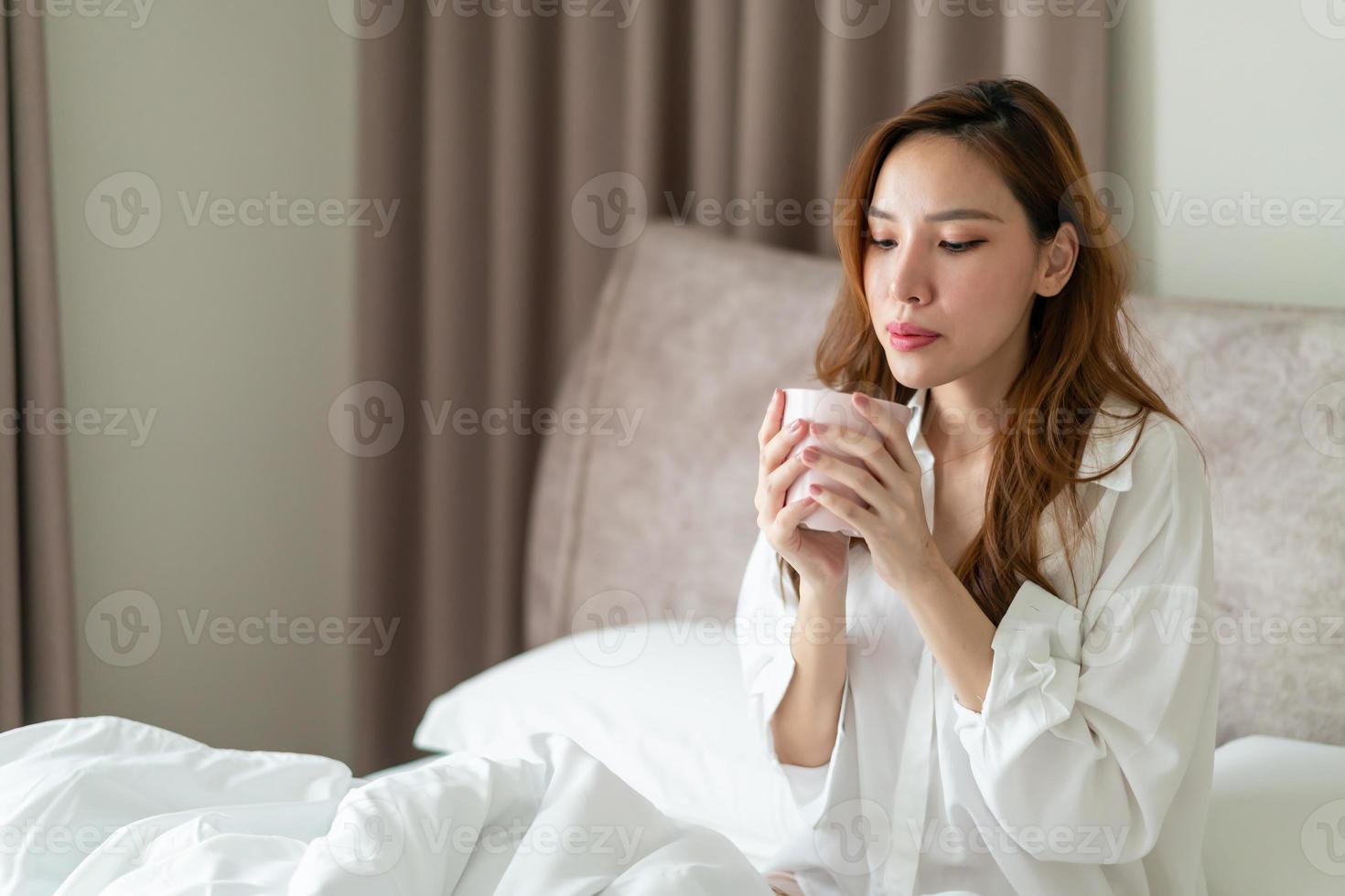 portrait belle femme se réveiller et tenant une tasse de café ou une tasse sur le lit photo