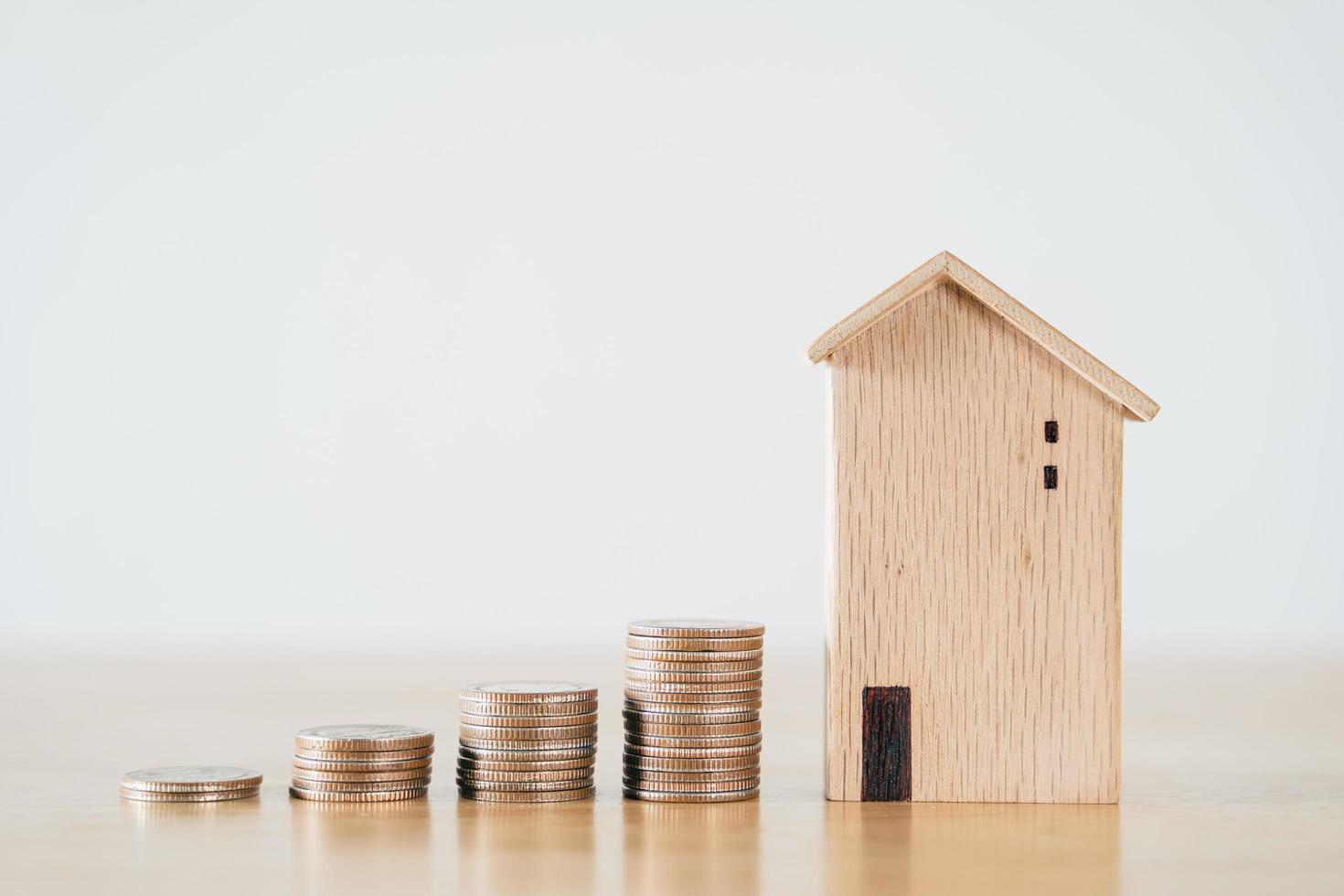 maison en bois et empiler des pièces sur une table en bois. économiser de l'argent pour acheter une maison, concept de prêt à domicile de plan financier. photo