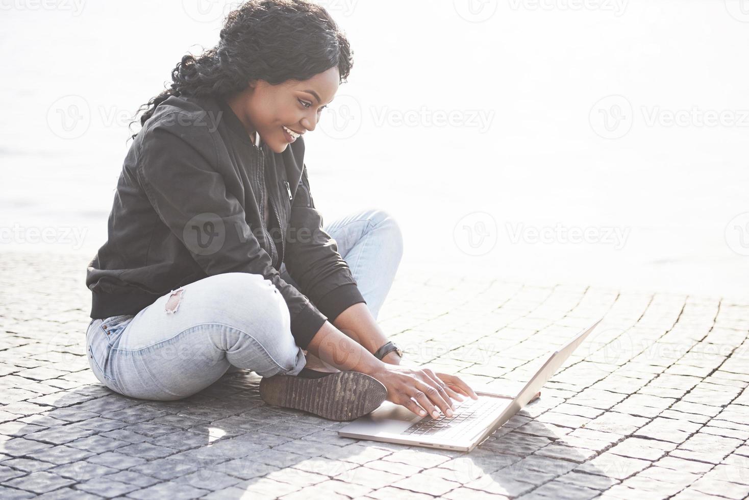 jeune femme dans la rue travaillant sur ordinateur portable photo