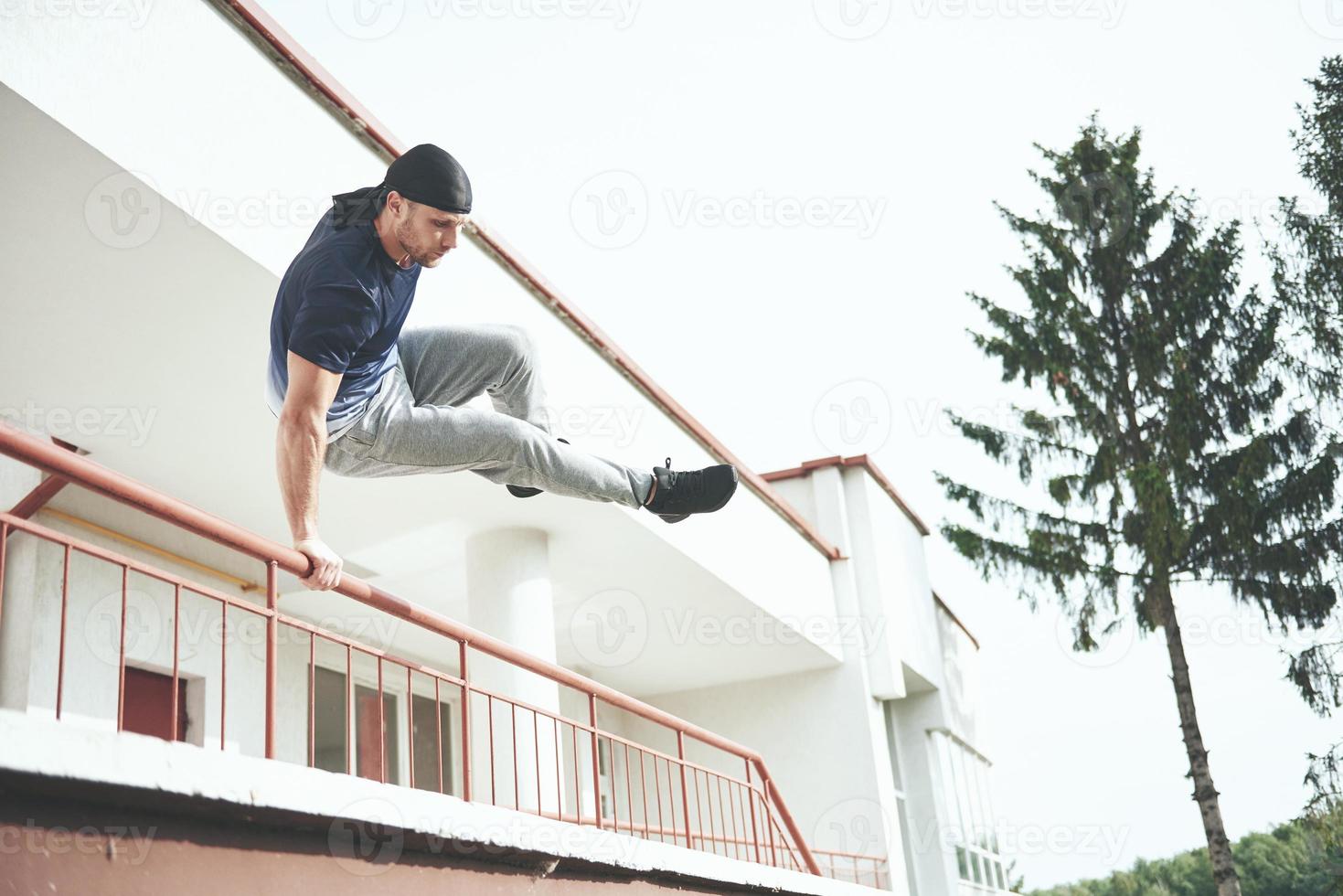 jeune homme faisant un saut de parkour dans l'espace urbain dans la ville ensoleillée de printemps été. photo