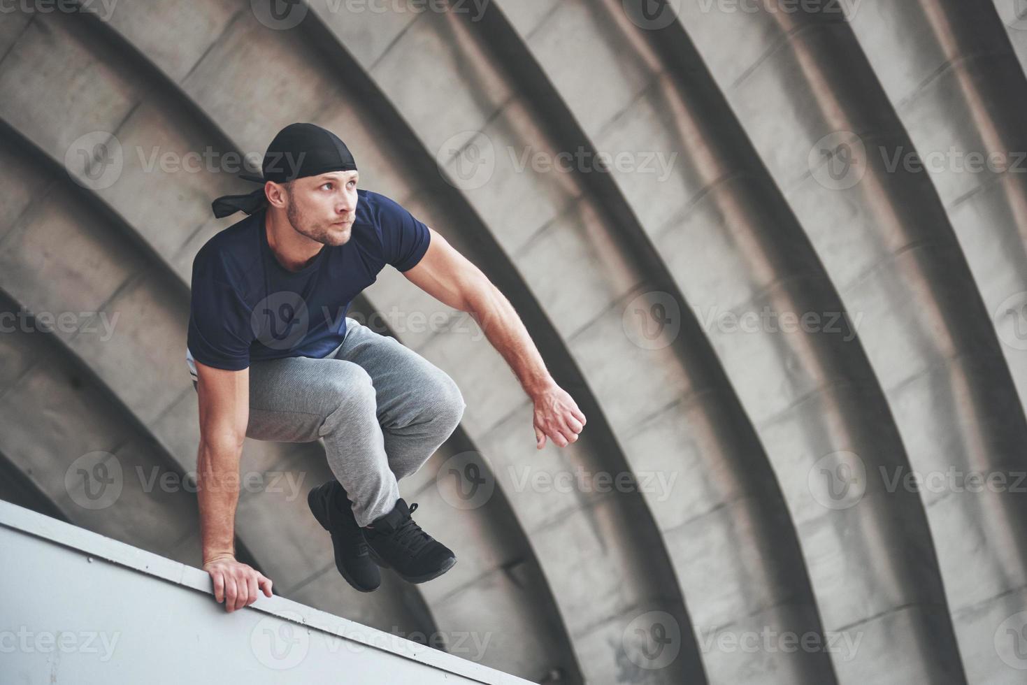 jeune homme faisant un saut de parkour dans l'espace urbain dans la ville ensoleillée de printemps été. photo