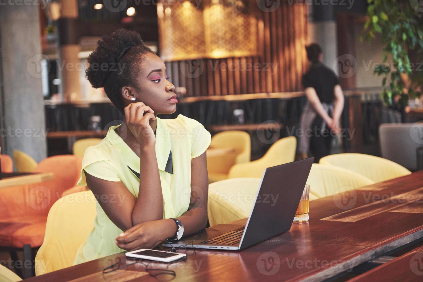 jeune fille afro-américaine aux cheveux noirs et bouclés pensif dans un café. photo