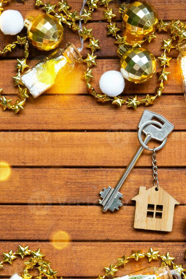 clé à maison avec une porte-clés minuscule Accueil sur en bois Contexte avec Noël décor mise en page. cadeau pour Nouveau année, Noël. bâtiment, projet, en mouvement à Nouveau loger, hypothèque, location et achat réel biens photo