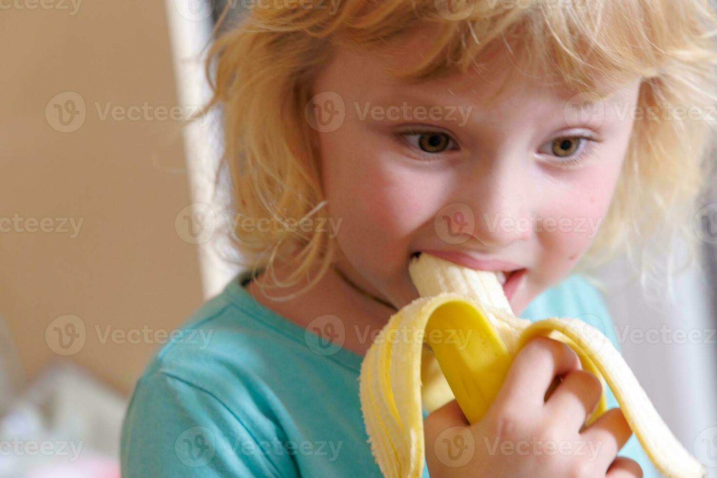 portrait de une peu fille en mangeant une banane. le concept de en bonne santé aliments. une Frais rapide casse-croûte photo