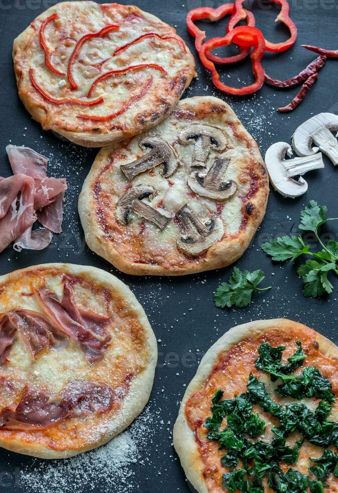 mini-pizzas avec diverses garnitures sur la planche de bois photo